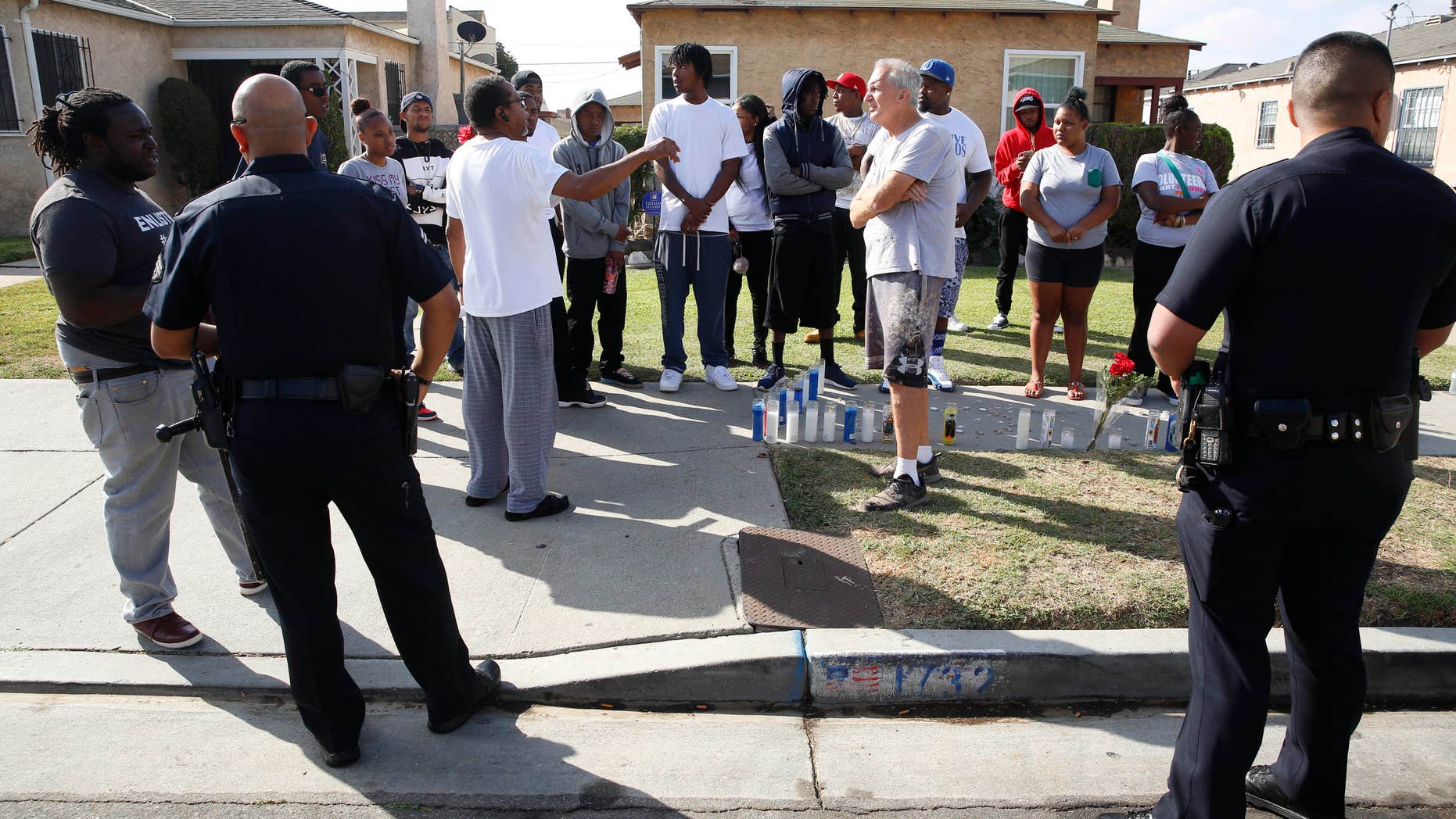 Oct. 2, 2016: Los Angeles Police officers speak to neighbors and members of the community gathered around a makeshift memorial outside a residence.