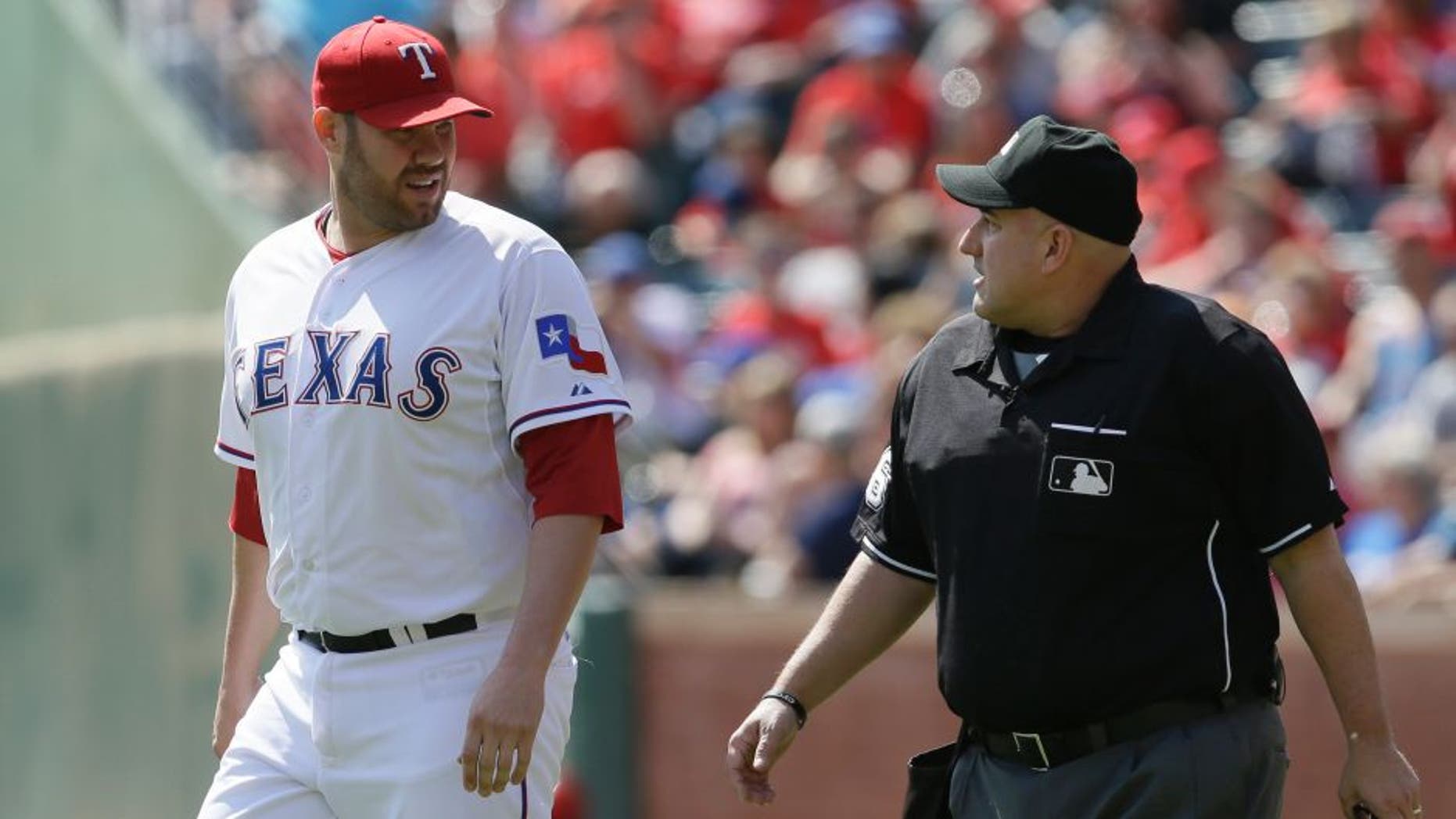 Texas Rangers starting pitcher Colby Lewis, left, discuses a call with home plate umpire Eric Cooper during the second inning of a baseball game against the Los Angeles Angels in Arlington, Texas, Saturday, Oct. 3, 2015. (AP Photo/LM Otero)