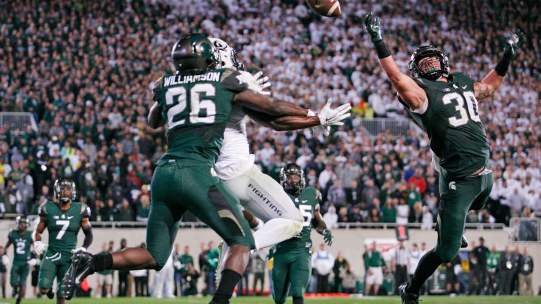 Sep 12, 2015; East Lansing, MI, USA; Michigan State Spartans linebacker Riley Bullough (30) and safety Rj Williamson (26) defend Oregon Ducks wide receiver Byron Marshall (9) during the fourth quarter at Spartan Stadium. Spartans beat the Ducks 31-28. Mandatory Credit: Raj Mehta-USA TODAY Sports