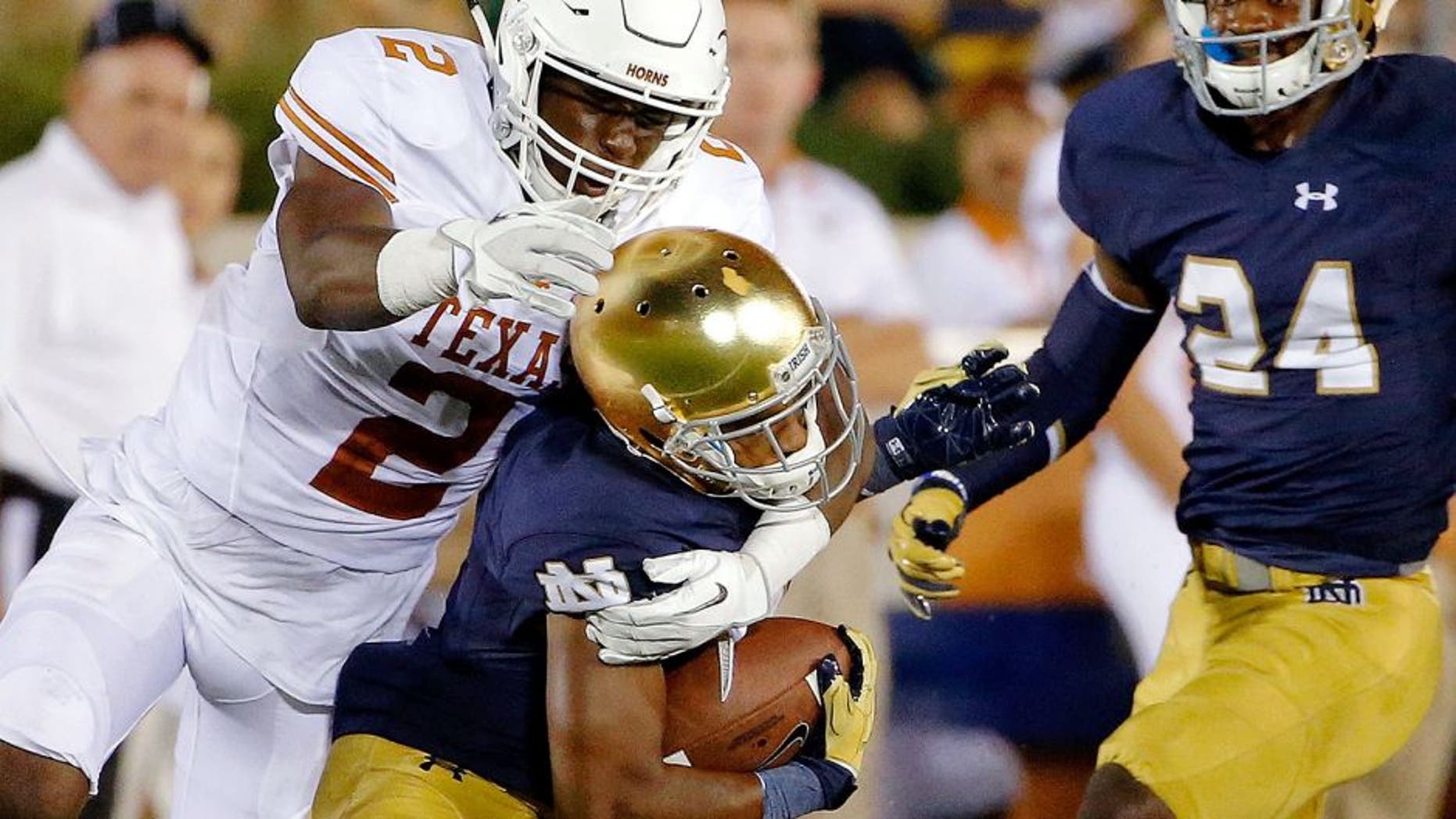 SOUTH BEND, IN - SEPTEMBER 05: Kris Boyd #2 of the Texas Longhorns tackles and dislodges the helmet of Jaylon Smith #9 of the Notre Dame Fighting Irish during the fourth quarter at Notre Dame Stadium on September 5, 2015 in South Bend, Indiana. The Notre Dame Fighting Irish won 38-3. (Photo by Jon Durr/Getty Images)