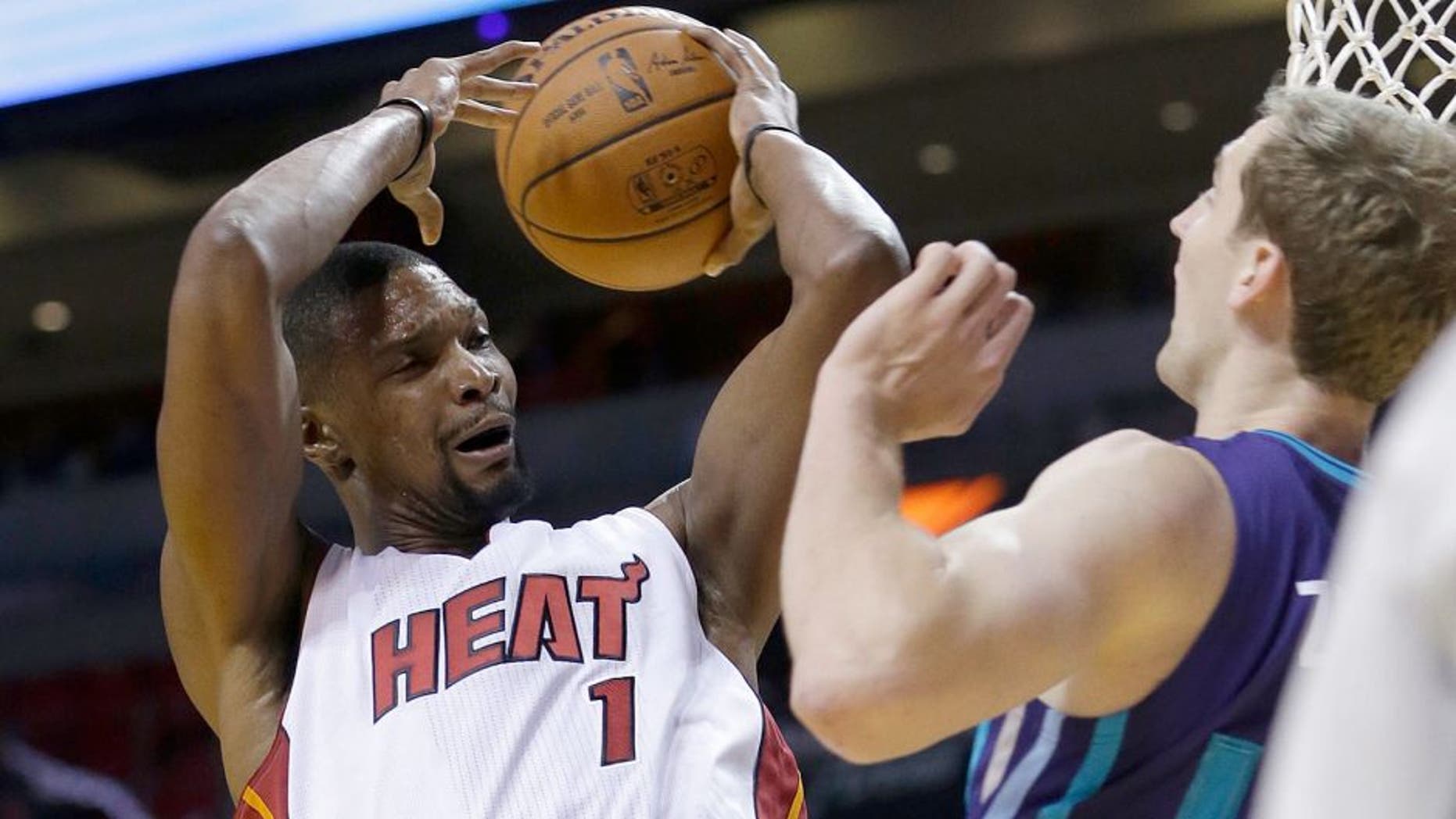 Miami Heat forward Chris Bosh (1) is fouled by Charlotte Hornets forward Cody Zeller (40) as Bosh goes to the basket in the first half of an NBA preseason basketball game, Sunday, Oct. 4, 2015, in Miami. (AP Photo/Alan Diaz)