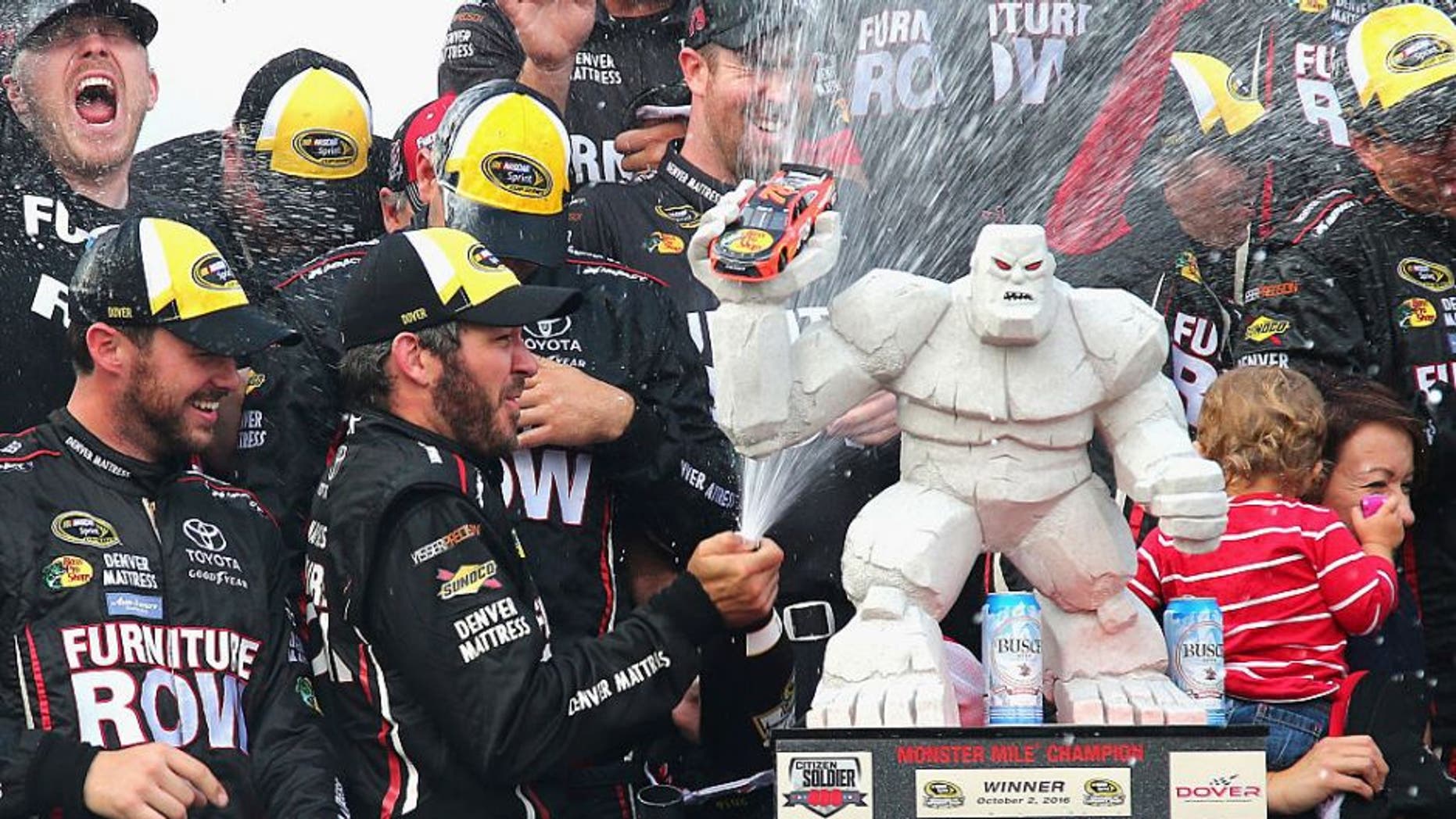 DOVER, DE - OCTOBER 02: Martin Truex Jr., driver of the #78 Furniture Row/Denver Mattress Toyota, celebrates with the trophy in Victory Lane after winning the NASCAR Sprint Cup Series Citizen Solider 400 at Dover International Speedway on October 2, 2016 in Dover, Delaware. (Photo by Sarah Crabill/NASCAR via Getty Images)