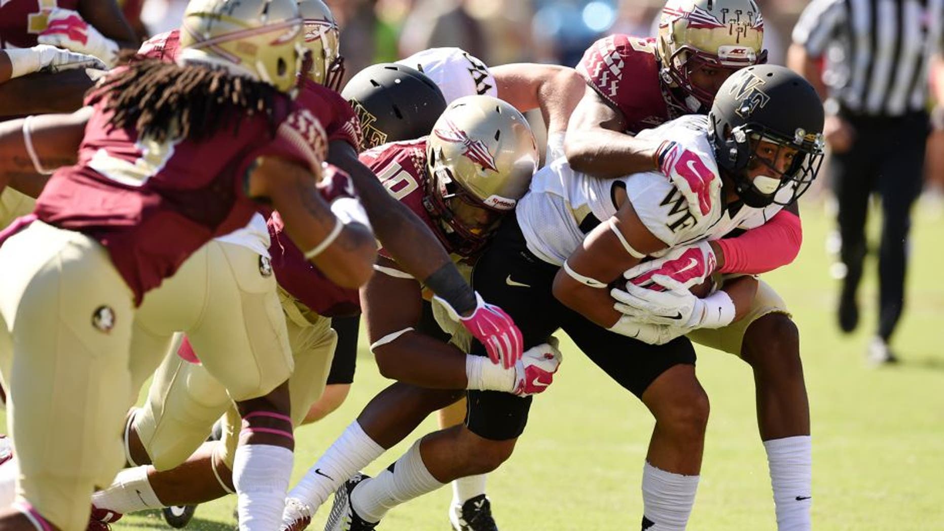 Oct 4, 2014; Tallahassee, FL, USA; Wake Forest Demon Deacons wide receiver Jared Crump (88) gets wrapped up by Florida State Seminoles linebacker E.J. Levenberry (10) and defensive back Jalen Ramsey (8) during the first quarter at Doak Campbell Stadium. Mandatory Credit: John David Mercer-USA TODAY Sports