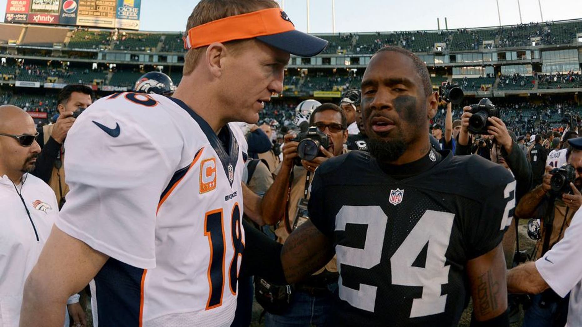 Dec 29, 2013; Oakland, CA, USA; Denver Broncos quarterback Peyton Manning (18) shakes hands with Oakland Raiders safety Charles Woodson (24) after the game at O.co Coliseum. The Broncos defeated the Raiders 34-14. Mandatory Credit: Kirby Lee-USA TODAY Sports
