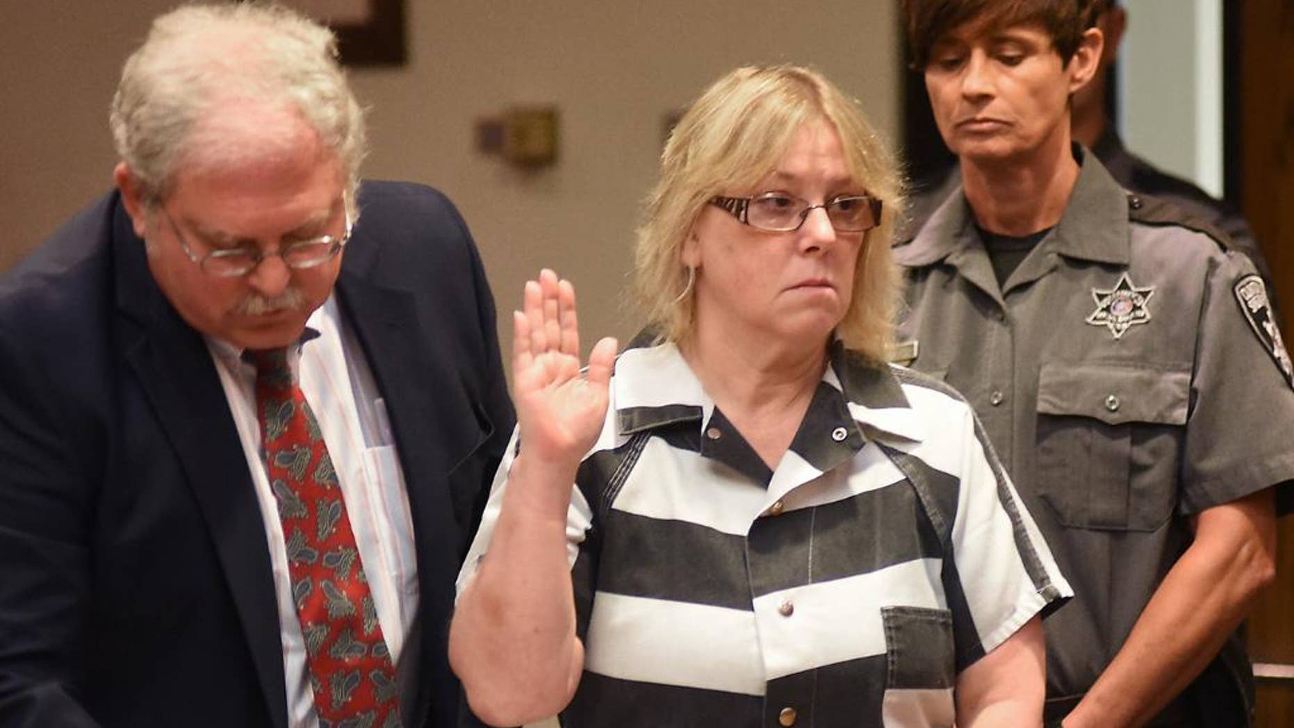 FILE - In this July 28, 2015 file photo, Joyce Mitchell raises her hand during a court appearance in Plattsburgh, N.Y. Mitchell, the former New York prison employee who helped two killers escape from a maximum-security prison in June, said in an interview that aired Monday, Sept. 14, on NBC's "Today" show that she was depressed at the time and the inmates took advantage of what she called her "weakness." (Rob Fountain/The Press-Republican via AP, Pool, File)