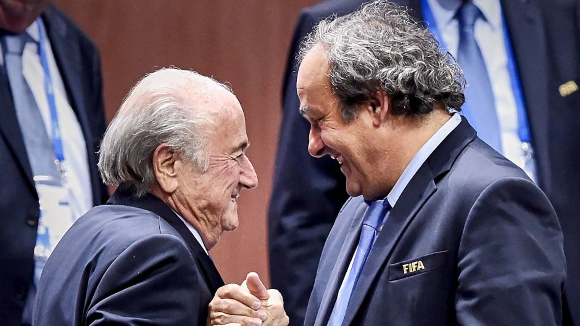 FIFA President Sepp Blatter (Foreground-L) shakes hands with UEFA president Michel Platini after being re-elected following a vote to decide on the FIFA presidency in Zurich on May 29, 2015. Sepp Blatter won the FIFA presidency for a fifth time after his challenger Prince Ali bin al Hussein withdrew just before a scheduled second round. AFP PHOTO / MICHAEL BUHOLZER (Photo credit should read MICHAEL BUHOLZER/AFP/Getty Images)