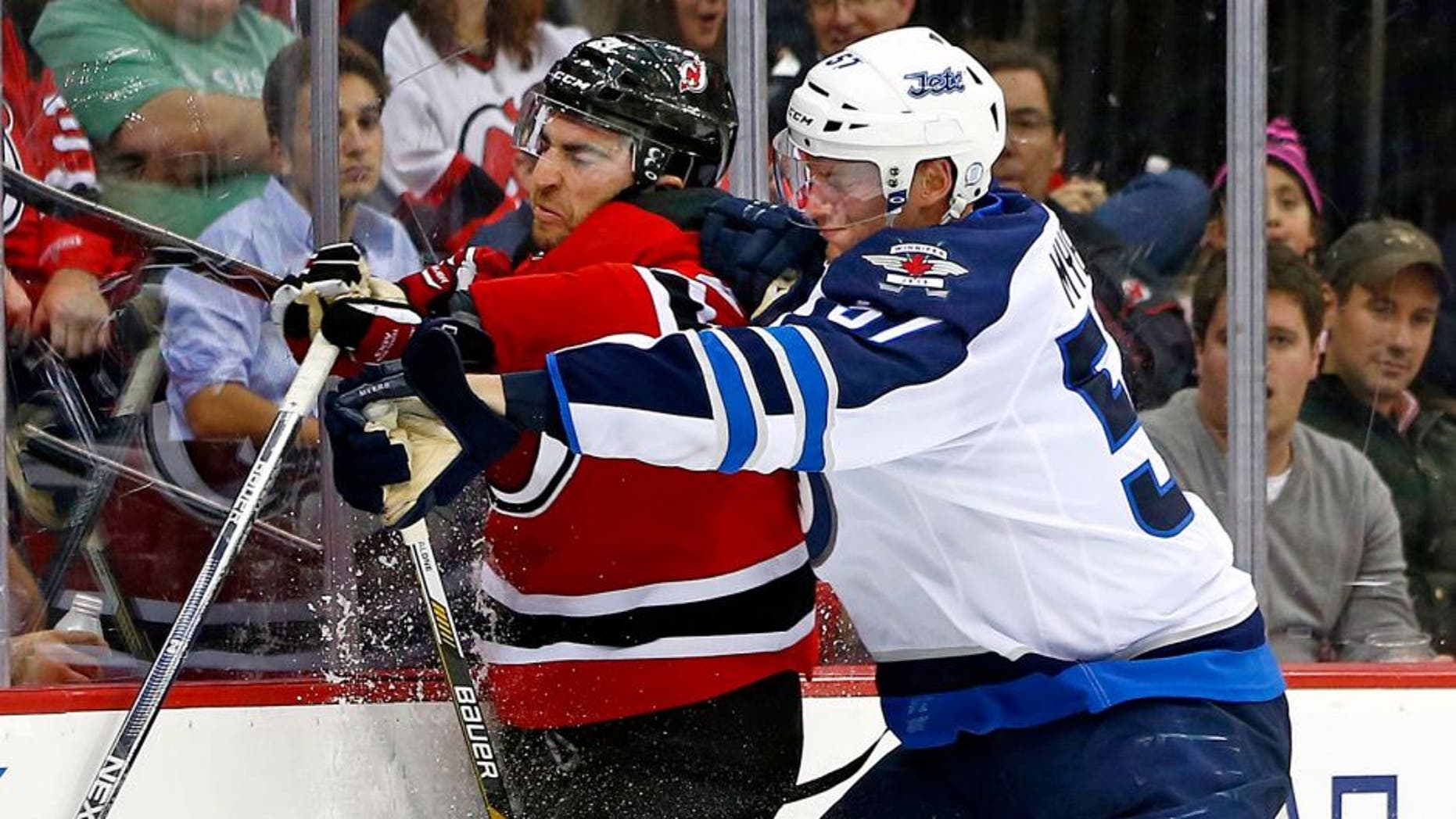 New Jersey Devils center Kyle Palmieri, left, is checked off the puck by Winnipeg Jets defensemen Tyler Myers (57) during the first period of an NHL hockey game in Newark, N.J., Friday, Oct. 9, 2015. The Jets defeated the Devils 3-1. (AP Photo/Rich Schultz)