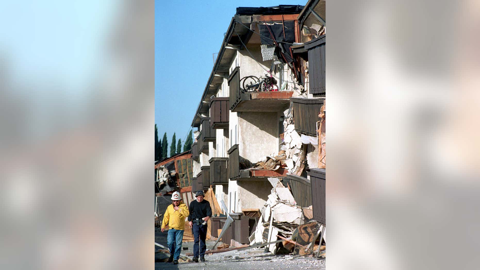 FILE - In this Jan.17, 1994, file photo, rescue workers walk past the Northridge Meadows Apartments that collapsed during the earthquake in Los Angeles.