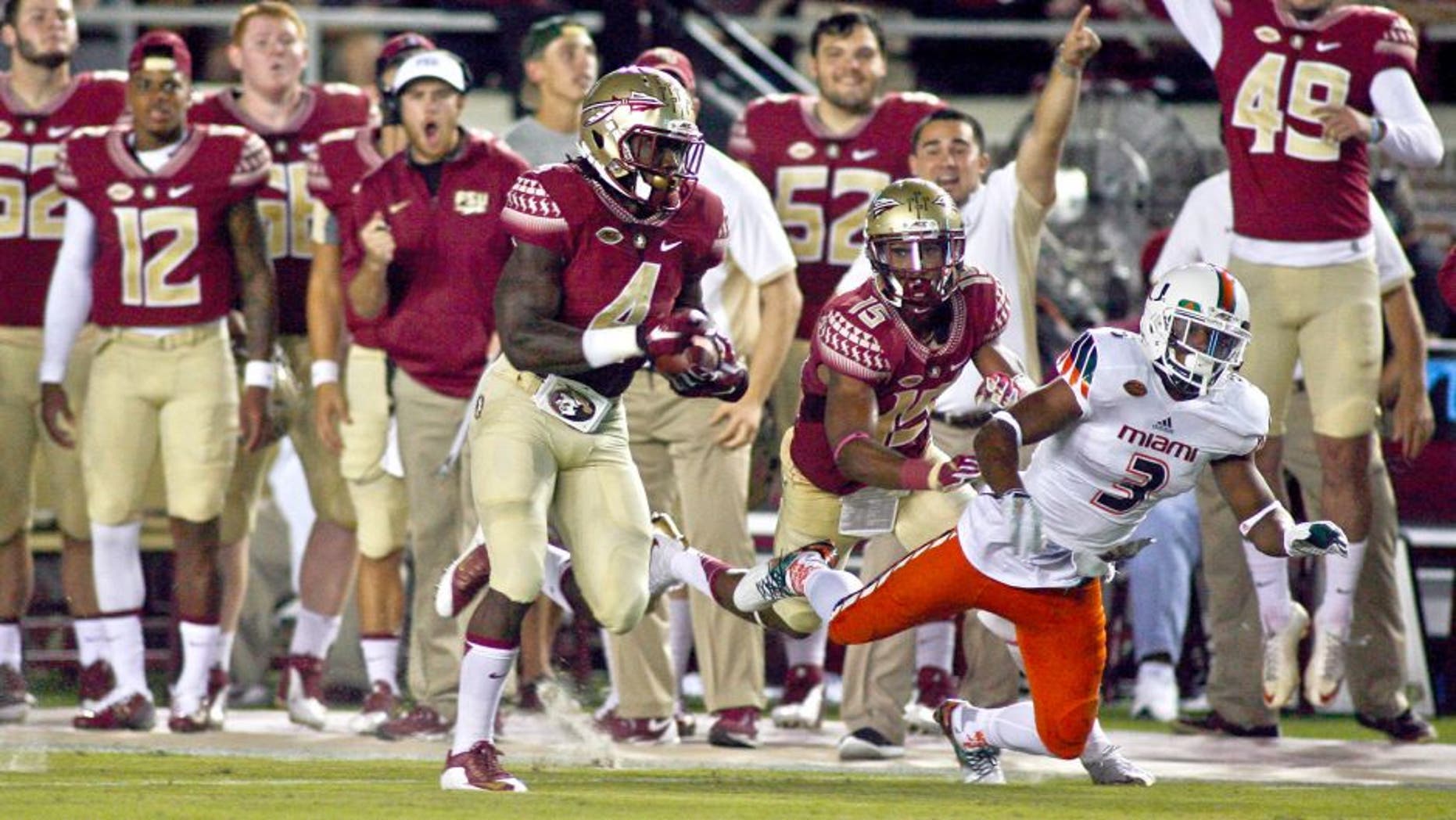Oct 10, 2015; Tallahassee, FL, USA; With a block on Miami Hurricanes defensive back Tracy Howard (3) by Florida State Seminoles wide receiver Travis Rudolph (15), Florida State Seminoles running back Dalvin Cook (4) runs for a 72-yard touchdown in the first quarter of their game at Doak Campbell Stadium. Mandatory Credit: Phil Sears-USA TODAY Sports