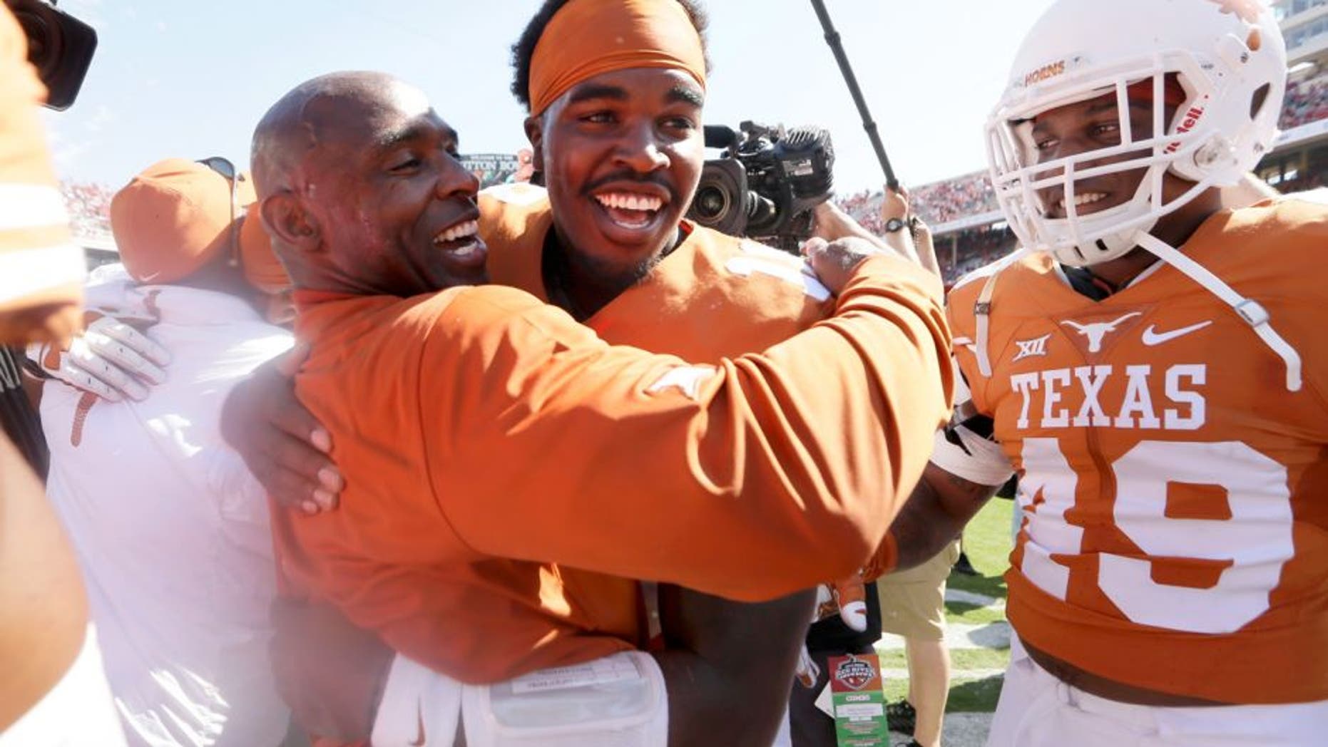Texas head coach Charlie Strong,center left, celebrates with Tyrone Swoopes after their 24-17 win over Oklahoma in an NCAA college football game, Saturday, Oct. 10, 2015, in Dallas. (AP Photo/LM Otero)