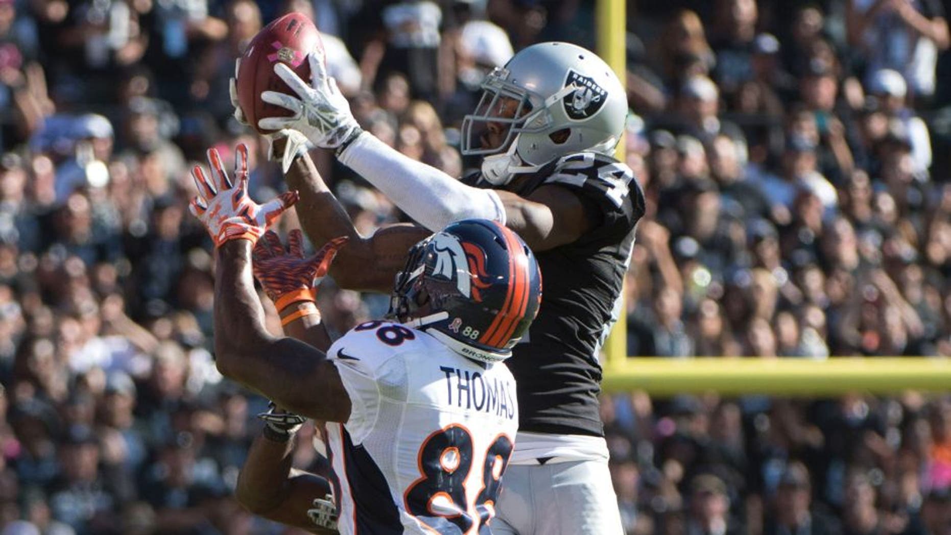 October 11, 2015; Oakland, CA, USA; Oakland Raiders free safety Charles Woodson (24) intercepts the football intended for Denver Broncos wide receiver Demaryius Thomas (88) during the third quarter at O.co Coliseum. The Raiders defeated the Broncos 16-10. Mandatory Credit: Kyle Terada-USA TODAY Sports