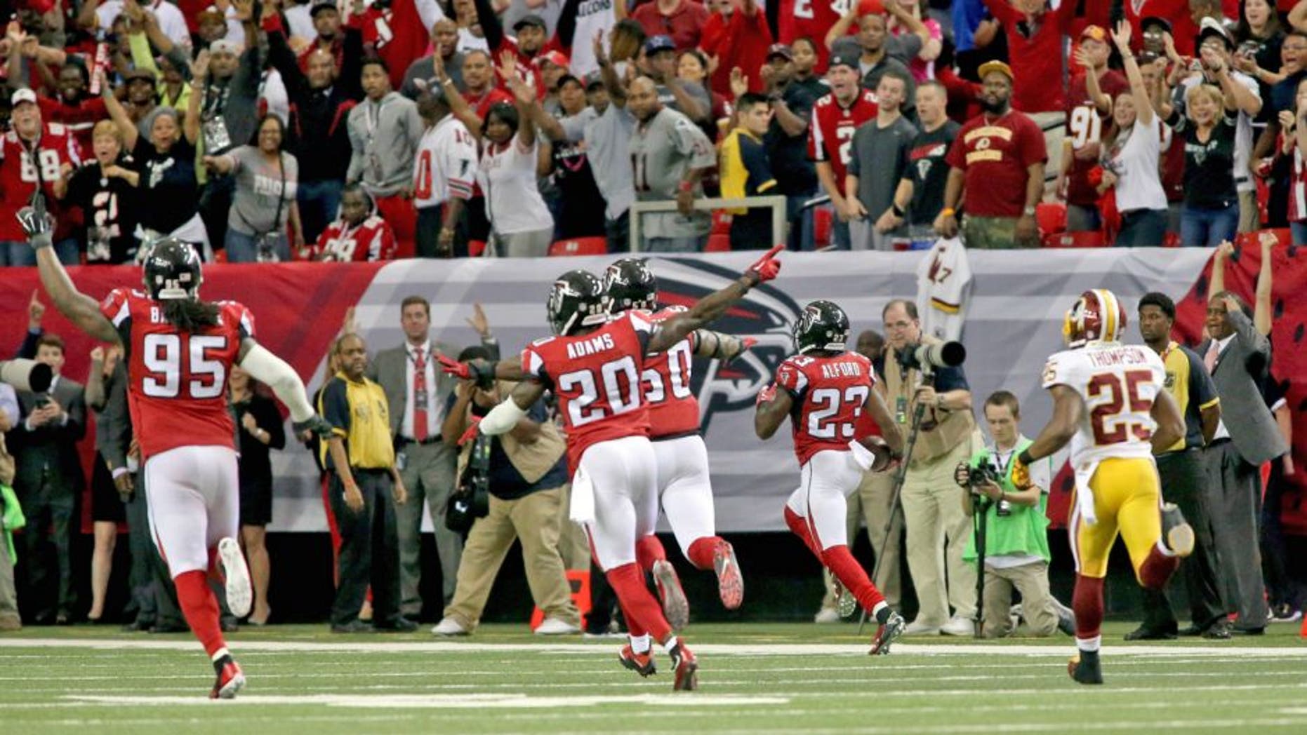 Oct 11, 2015; Atlanta, GA, USA; Atlanta Falcons defensive tackle Jonathan Babineaux (95) and defensive back Phillip Adams (20) celebrate as cornerback Robert Alford (23, right) returns an interception for a touchdown to win the game in overtime against the Washington Redskins at the Georgia Dome. The Falcons won 25-19 in overtime. Mandatory Credit: Jason Getz-USA TODAY Sports