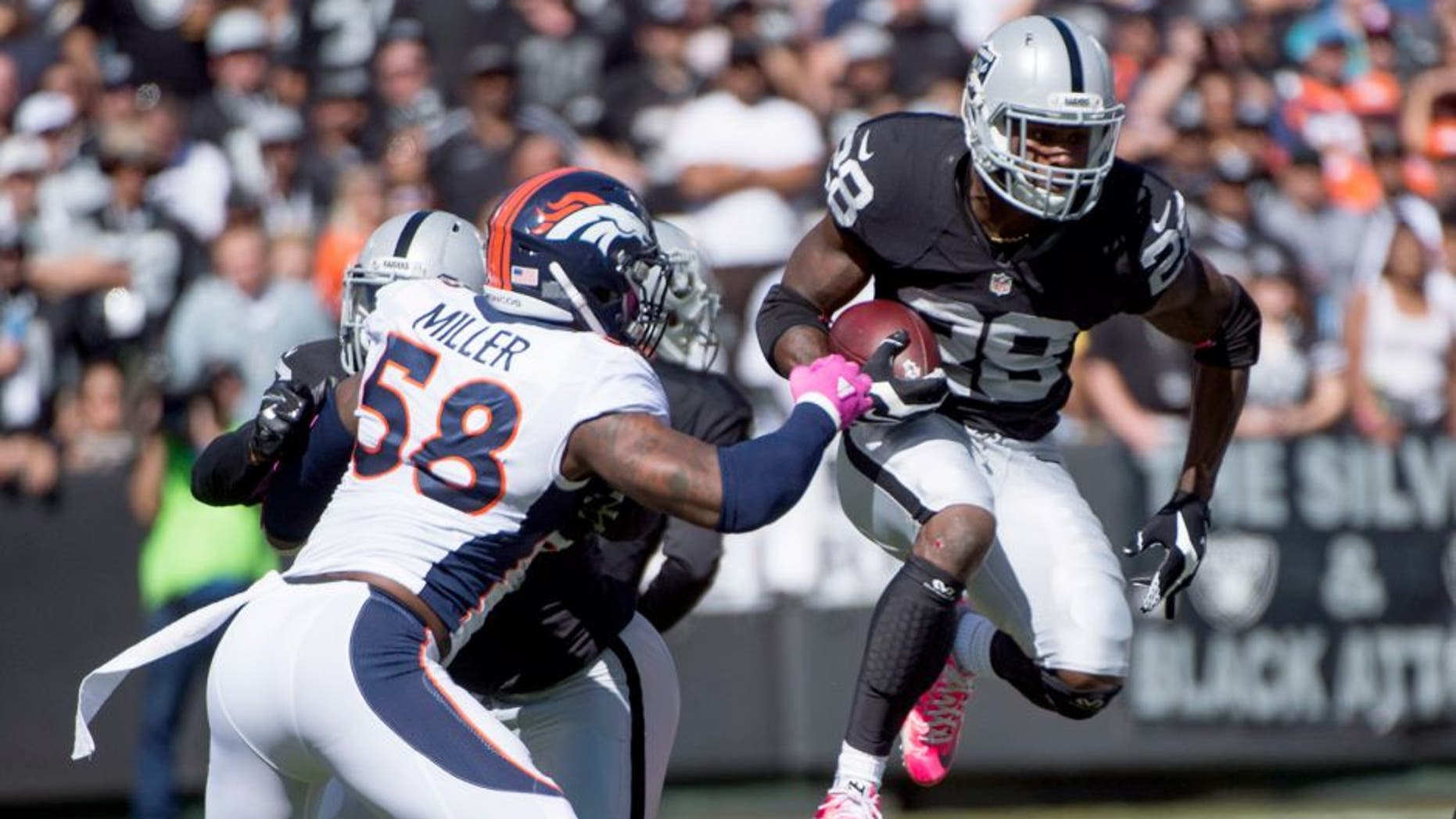 October 11, 2015; Oakland, CA, USA; Oakland Raiders running back Latavius Murray (28) runs with the football against Denver Broncos outside linebacker Von Miller (58) during the first quarter at O.co Coliseum. Mandatory Credit: Kyle Terada-USA TODAY Sports