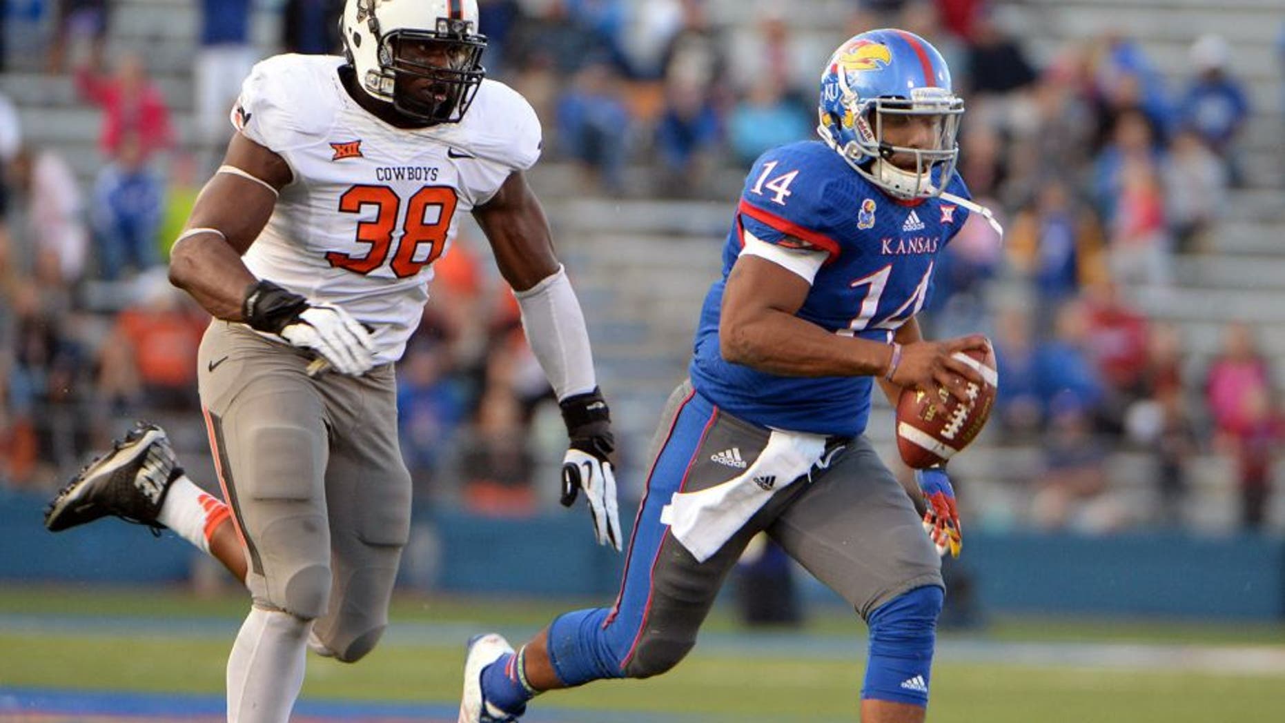Oct 11, 2014; Lawrence, KS, USA; Kansas Jayhawks quarterback Michael Cummings (14) is chased by Oklahoma State Cowboys defensive end Emmanuel Ogbah (38) in the second half at Memorial Stadium. Oklahoma State won the game 27-20. Mandatory Credit: John Rieger-USA TODAY Sports