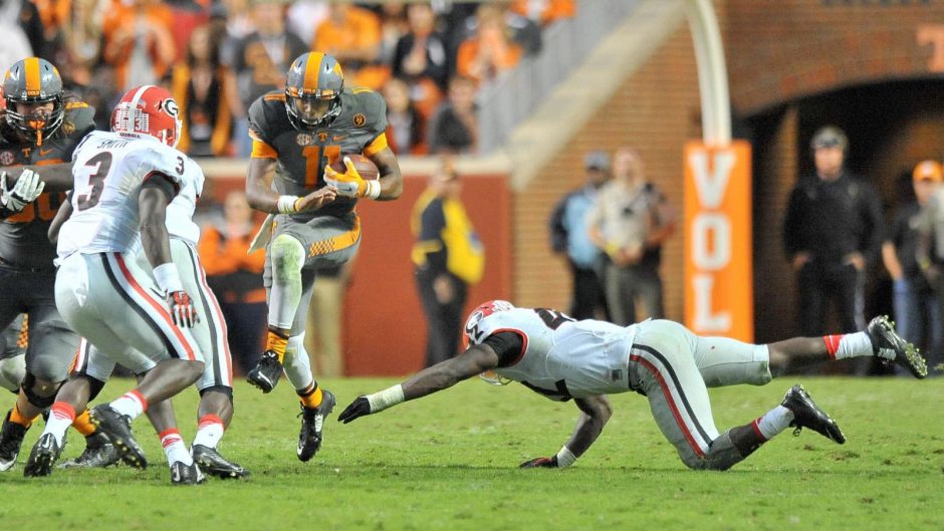 Oct 10, 2015; Knoxville, TN, USA; Tennessee Volunteers quarterback Joshua Dobbs (11) rushes against Georgia Bulldogs linebacker Tim Kimbrough (42) and Bulldogs linebacker Roquan Smith (3) during the second half at Neyland Stadium. Tennessee won 38-31. Mandatory Credit: Jim Brown-USA TODAY Sports