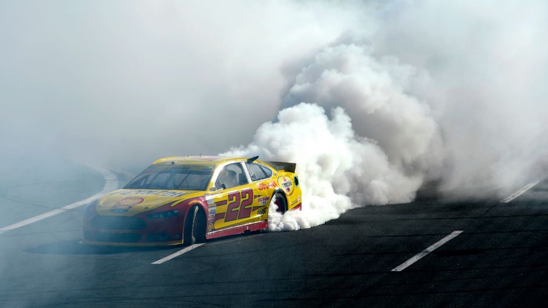 CHARLOTTE, NC - OCTOBER 11: Joey Logano, driver of the #22 Shell Pennzoil Ford, celebrates with a burnout after winning the NASCAR Sprint Cup Series Bank of America 500 at Charlotte Motor Speedway on October 11, 2015 in Charlotte, North Carolina. (Photo by Robert Laberge/NASCAR via Getty Images)