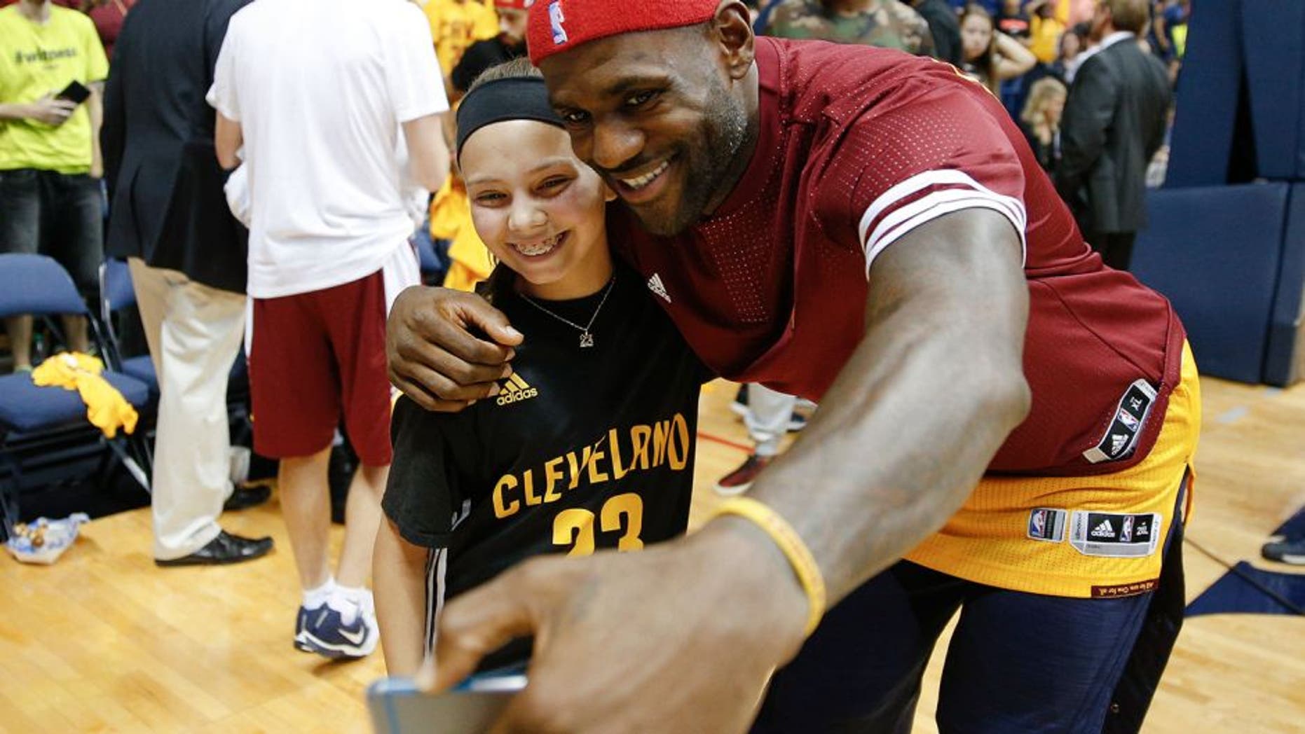 Cleveland Cavaliers forward LeBron James, right, takes a selfie with a young fan after an NBA preseason basketball game against the Atlanta Hawks, Wednesday, Oct. 7, 2015, in Cincinnati. The Hawks won 98-96. (AP Photo/John Minchillo)