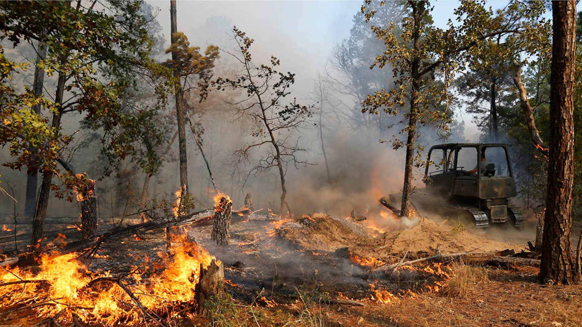 Oct. 14, 2015: Firefighters work with heavy machinery to contain the fire near Smithville, Texas.