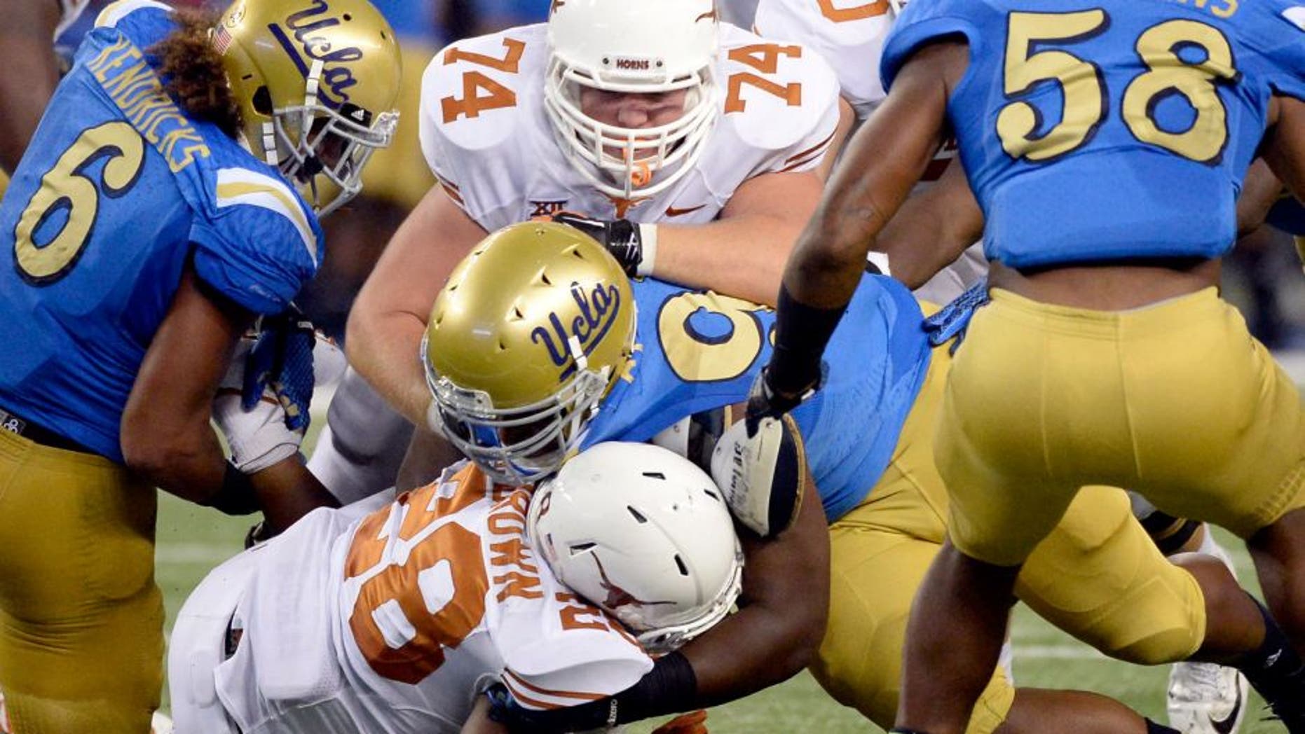 Sep 13, 2014; Arlington, TX, USA; Texas Longhorns guard Taylor Doyle (74) and running back Malcolm Brown (28) tackle UCLA Bruins defensive lineman Kenny Clark (97) during the second half at AT&T Stadium. Mandatory Credit: Richard Mackson-USA TODAY Sports