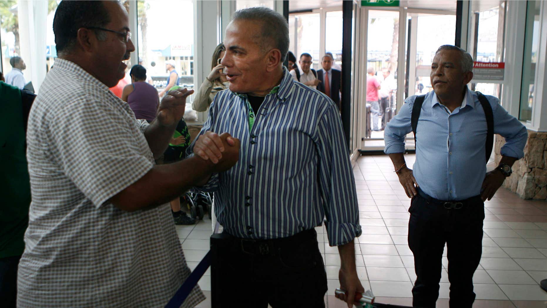 Oct. 15, 2015: A unidentified man shake hands with Venezuelan opposition leader Manuel Rosales, center, before he flies to Venezuela, at the airport near Oranjestad, Aruba.