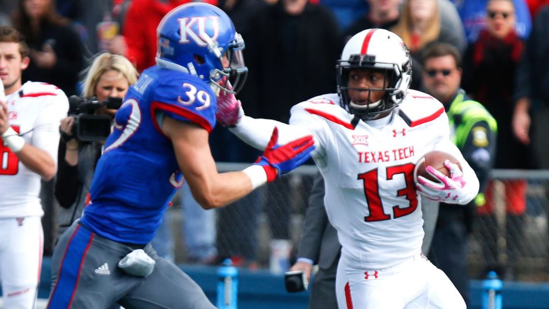 LAWRENCE, KS - OCTOBER 17: Cameron Batson #13 of the Texas Tech Red Raiders fends off Michael Glatczak #39 of the Kansas Jayhawks during the game on October 17, 2015 at Memorial Stadium in Lawrence, Kansas. (Photo by Kyle Rivas/Getty Images)