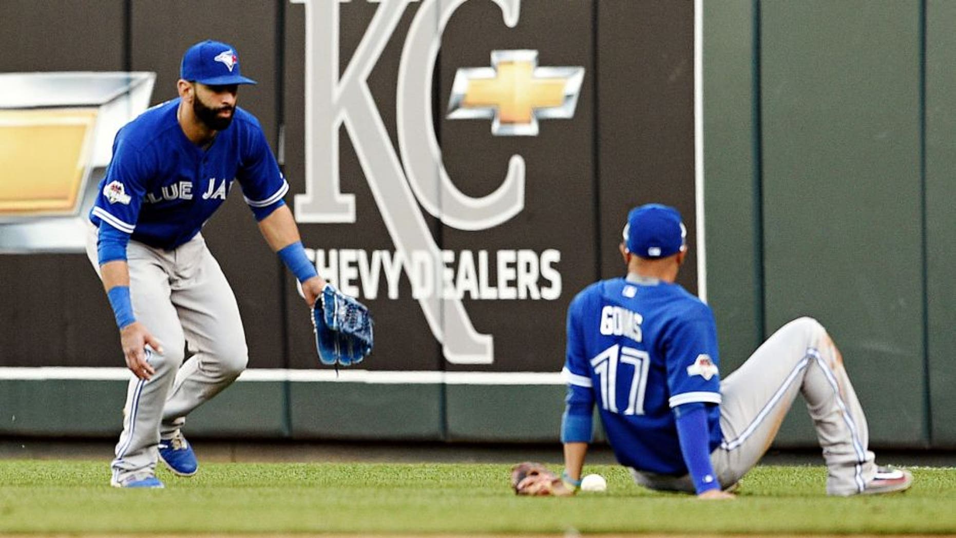 Toronto Blue Jays second baseman Ryan Goins sits on the ground and looks at the fly ball tha fell between himself and right fielder Jose Bautista, left, on a ball hit by the Kansas City Royals' Ben Zobrist in the seventh inning during Game 2 of the ALCS on at Kauffman Stadium in Kansas City, Mo., on Saturday, Oct. 17, 2015. (Shane Keyser/Kansas City Star/TNS via Getty Images)