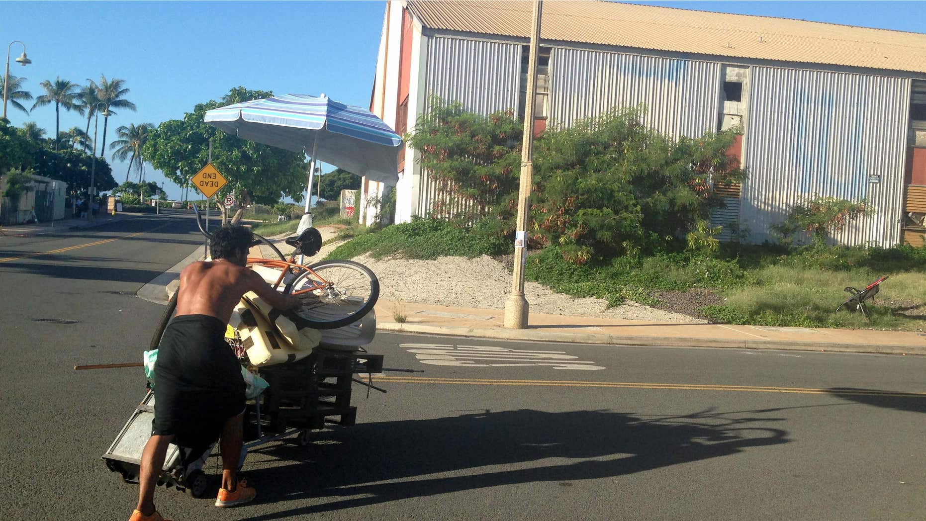 Oct. 8, 2015: A homeless man who had been living in a large encampment in the Kakaako neighborhood of Honolulu pushes his bleongings away from the camp as city officials sweep the area.