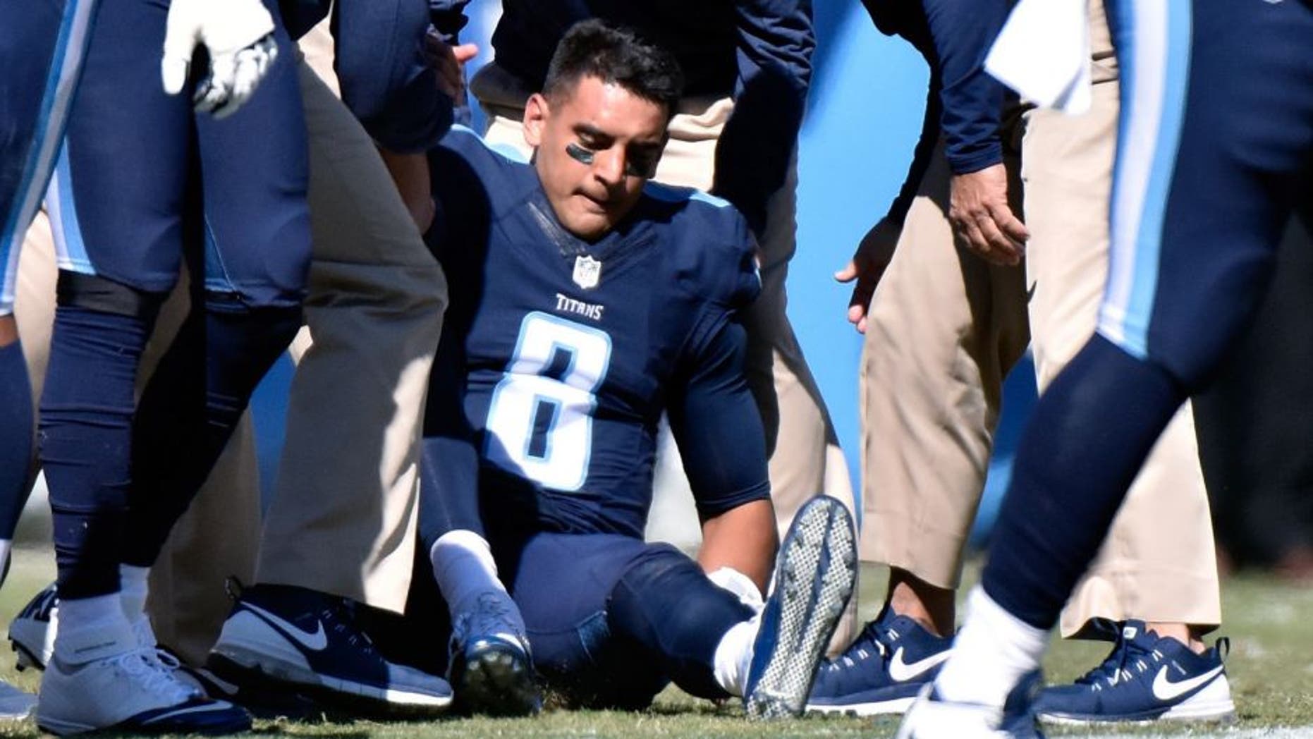 NASHVILLE, TN - OCTOBER 18: Quarterback Marcus Mariota #8 of the Tennessee Titans is attended to by medical staff after receiving a late hit by the Miami Dolphins during the first half of a game at Nissan Stadium on October 18, 2015 in Nashville, Tennessee. (Photo by Frederick Breedon/Getty Images)