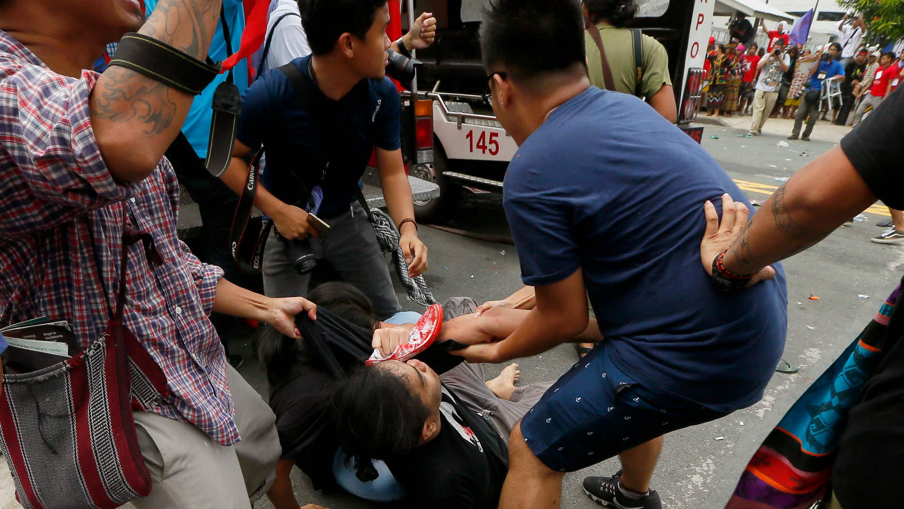 Oct. 19, 2016: A protester is helped after a Philippine National Police van, background, rammed into protesters outside the U.S. Embassy in Manila, Philippines injuring an undetermined number.