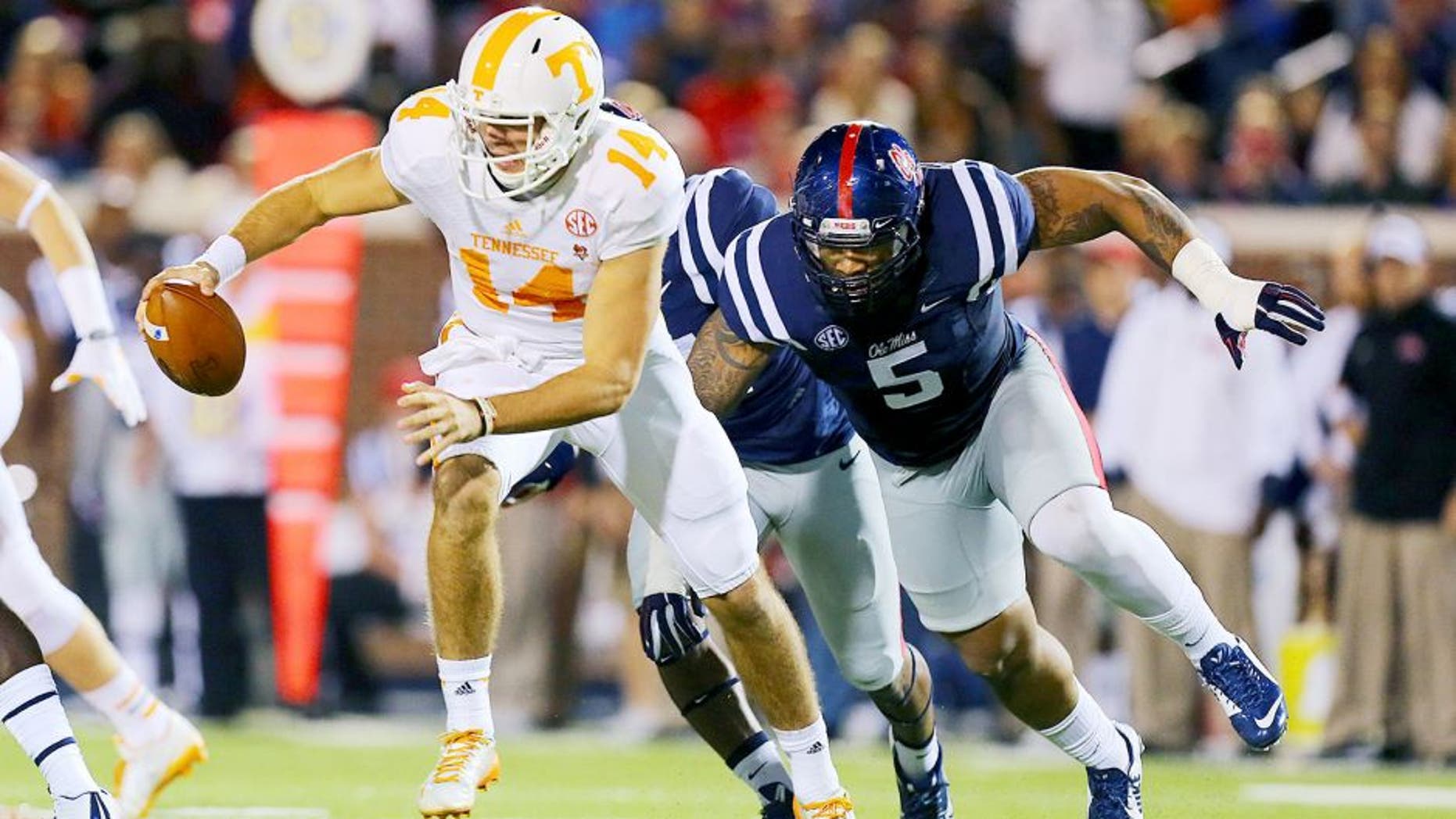 Oct 18, 2014; Oxford, MS, USA; Tennessee Volunteers quarterback Justin Worley (14) advances the ball while being chased by Mississippi Rebels defensive tackle Robert Nkemdiche (5) during the game at Vaught-Hemingway Stadium. Mandatory Credit: Spruce Derden-USA TODAY Sports