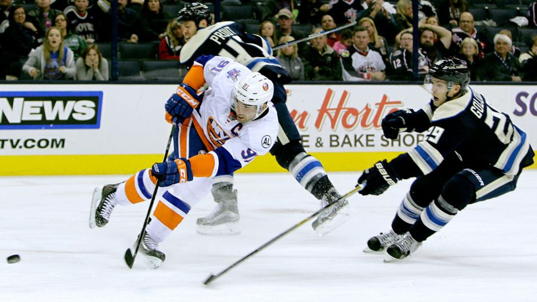 New York Islanders' John Tavares, left, shoots and scores a goal between Columbus Blue Jackets' Dalton Prout, back, and Cody Goloubef during the third period of an NHL hockey game Tuesday, Oct. 20, 2015, in Columbus, Ohio. The Islanders beat the Blue Jackets 4-0. (AP Photo/Jay LaPrete)