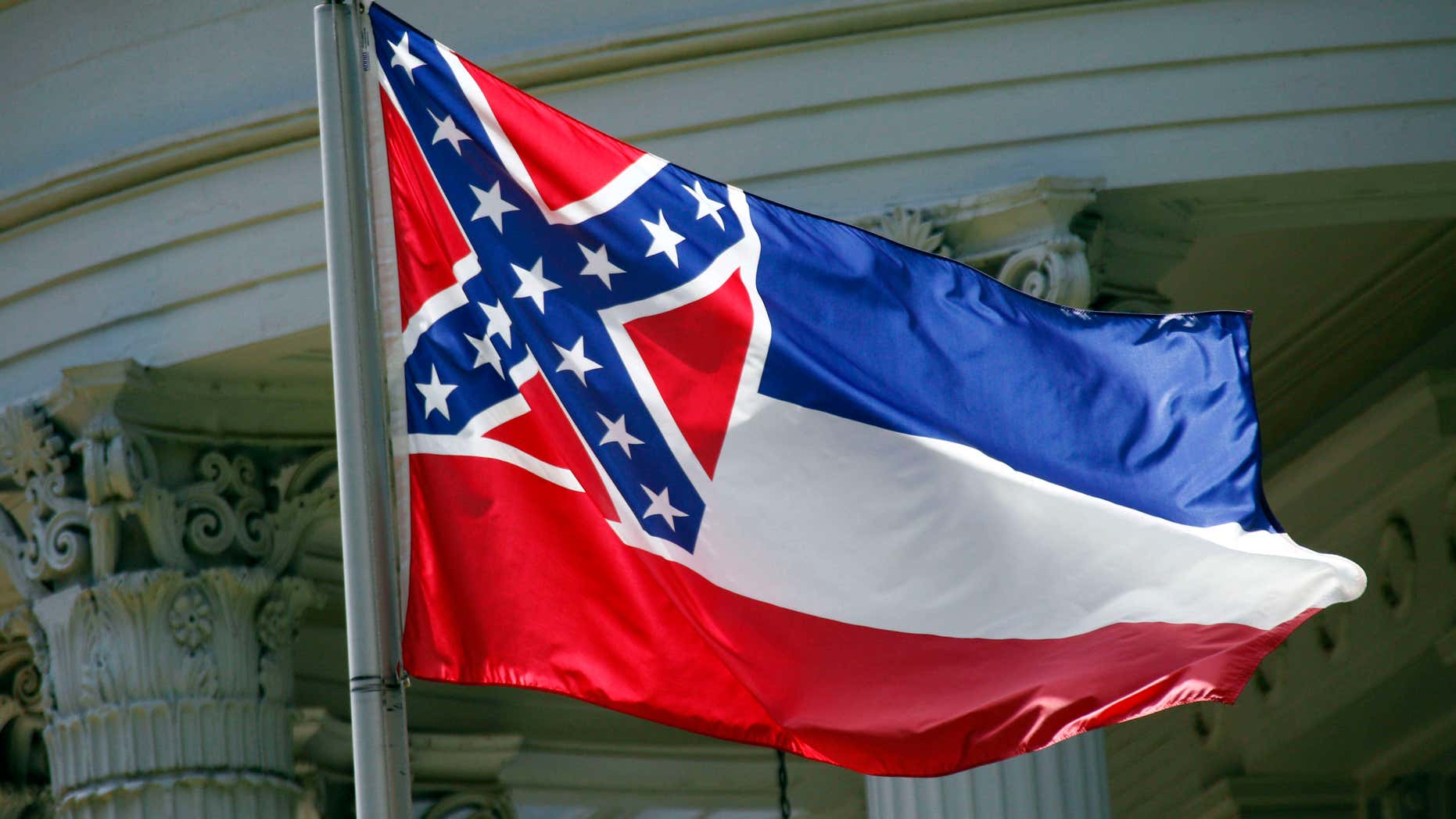 In this photo taken June 23, 2015, the Mississippi state flag is unfurled against the front of the Governor's Mansion in Jackson, Miss.