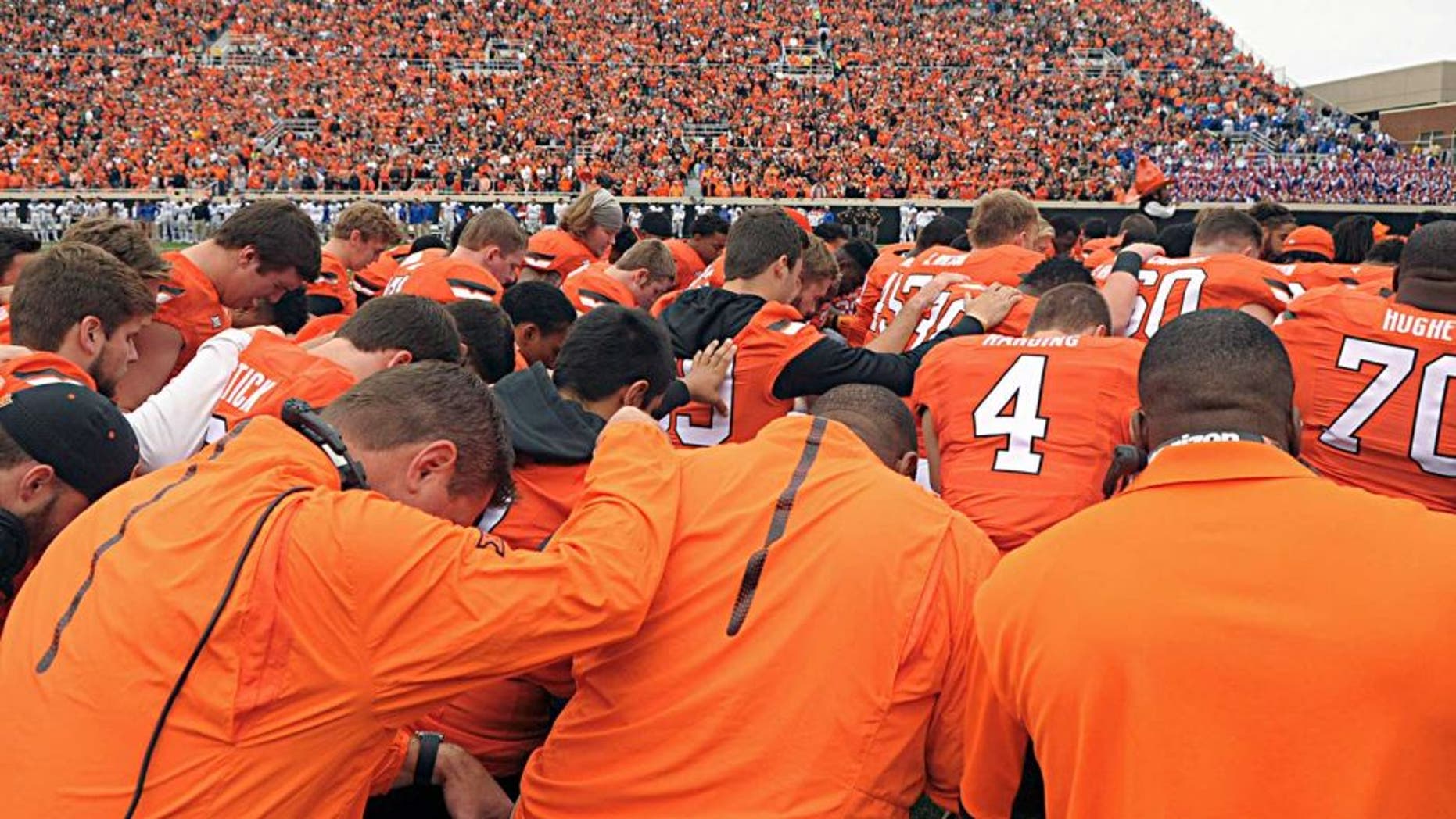 Oklahoma State players and staff form a prayer circle prior to an NCAA college football game between Kansas and Oklahoma St in Stillwater, Okla., Saturday, Oct. 24, 2015. Earlier in the day tragedy struck at the Oklahoma State homecoming parade as a car ran into a group of parade watchers killing at least three and injuring dozens more. (AP Photo/Brody Schmidt)