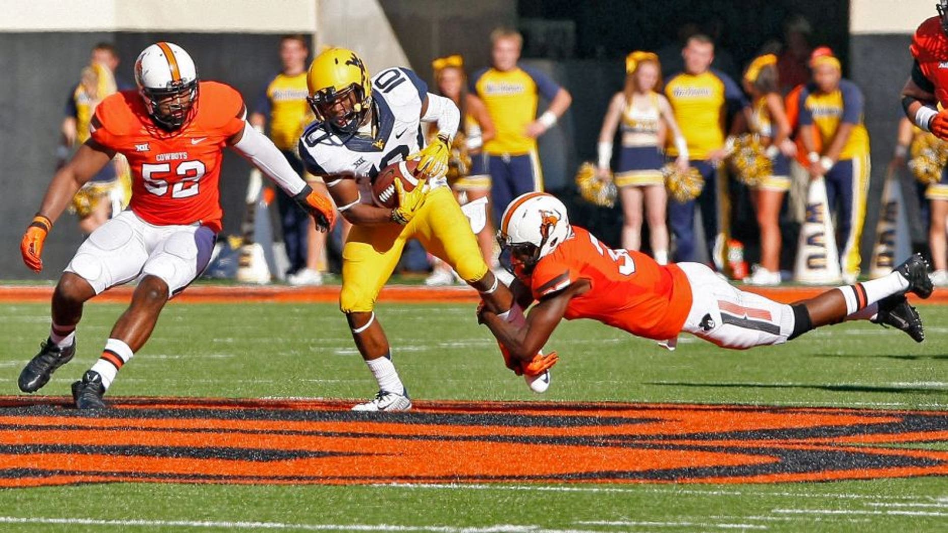 Oct 25, 2014; Stillwater, OK, USA; West Virginia Mountaineers wide receiver Jordan Thompson (center) is tackled by Oklahoma State Cowboys linebacker Ryan Simmons (left) and safety Tre Flowers (right) during the second quarter at Boone Pickens Stadium. Mandatory Credit: Alonzo Adams-USA TODAY Sports