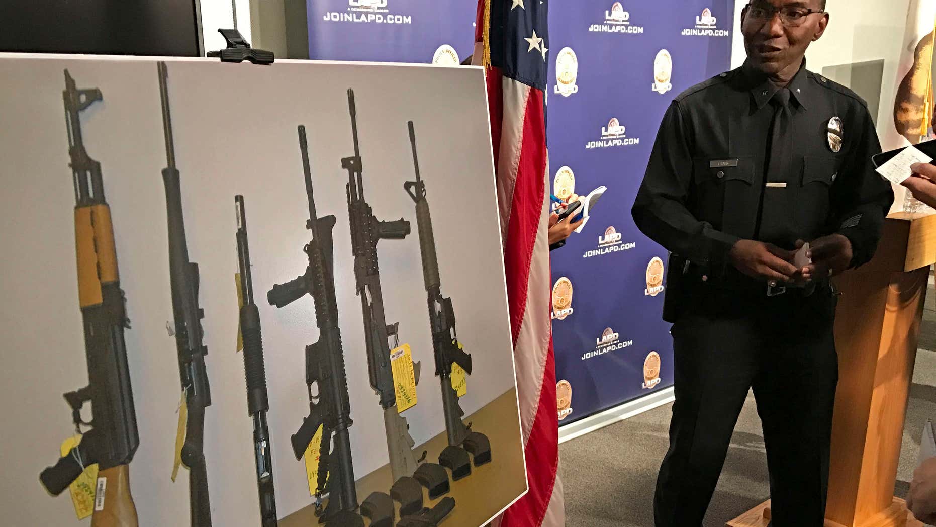 Los Angeles Police Cmdr. Horace Frank, right, shows a photo of multiple weapons found in the home of a man charged with making terrorist threats to the Islamic Center of Southern California, during a police news conference Tuesday, Oct. 25, 2016 in Los Angeles.