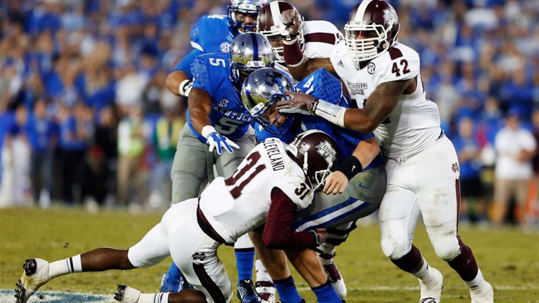 Oct 25, 2014; Lexington, KY, USA; Mississippi State Bulldogs defensive back Tolando Cleveland (31) and linebacker Beniquez Brown (42) tackle Kentucky Wildcats quarterback Patrick Towles (14) in the second half at Commonwealth Stadium. Mississippi State defeated Kentucky 45-31. Mandatory Credit: Mark Zerof-USA TODAY Sports
