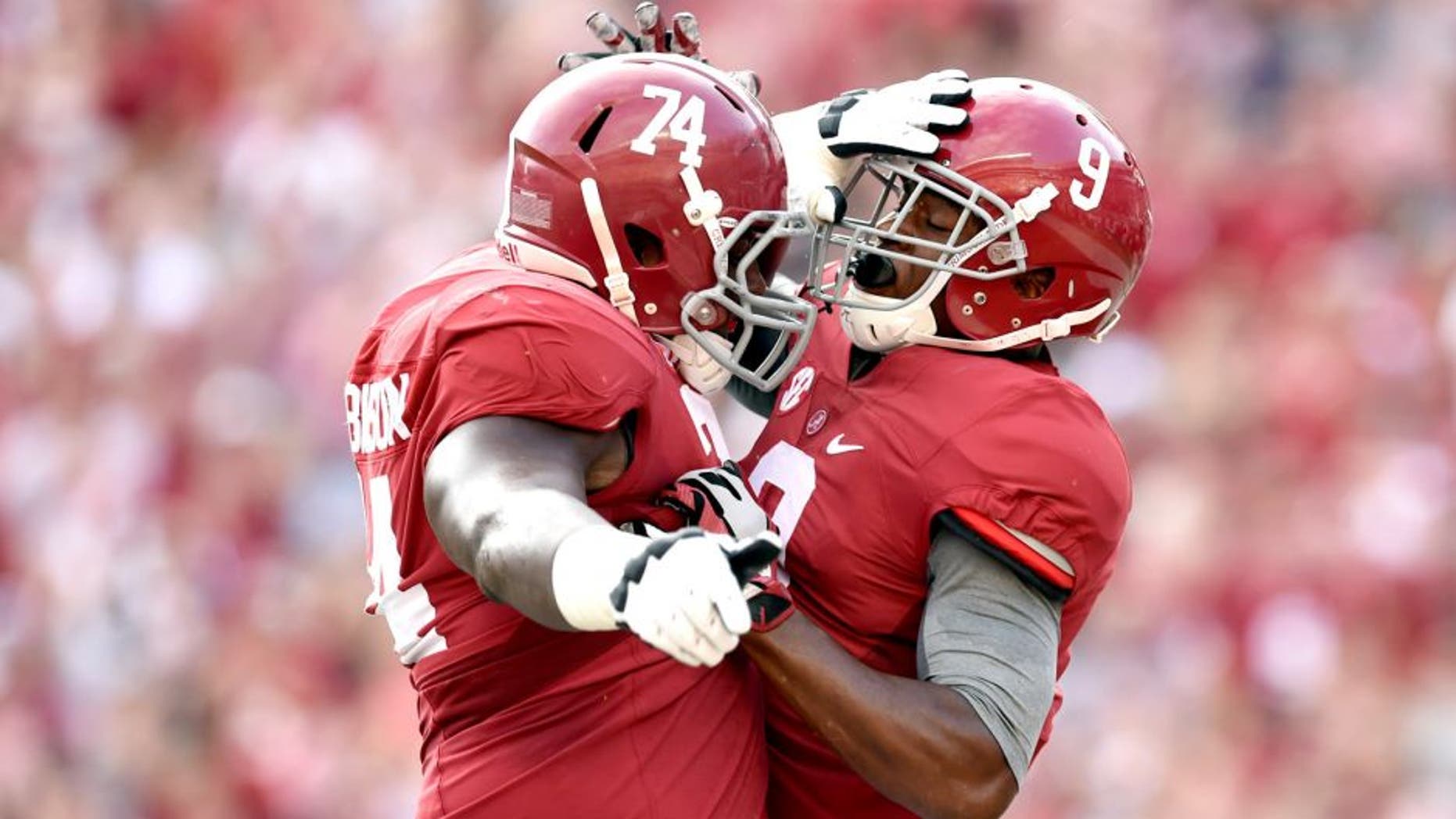 Sep 13, 2014; Tuscaloosa, AL, USA; Alabama Crimson Tide offensive linesman Cam Robinson (74) leaps up to celebrate wide receiver Amari Cooper (9) touchdown against the Southern Miss Golden Eagles during the first quarter at Bryant-Denny Stadium. Mandatory Credit: John David Mercer-USA TODAY Sports