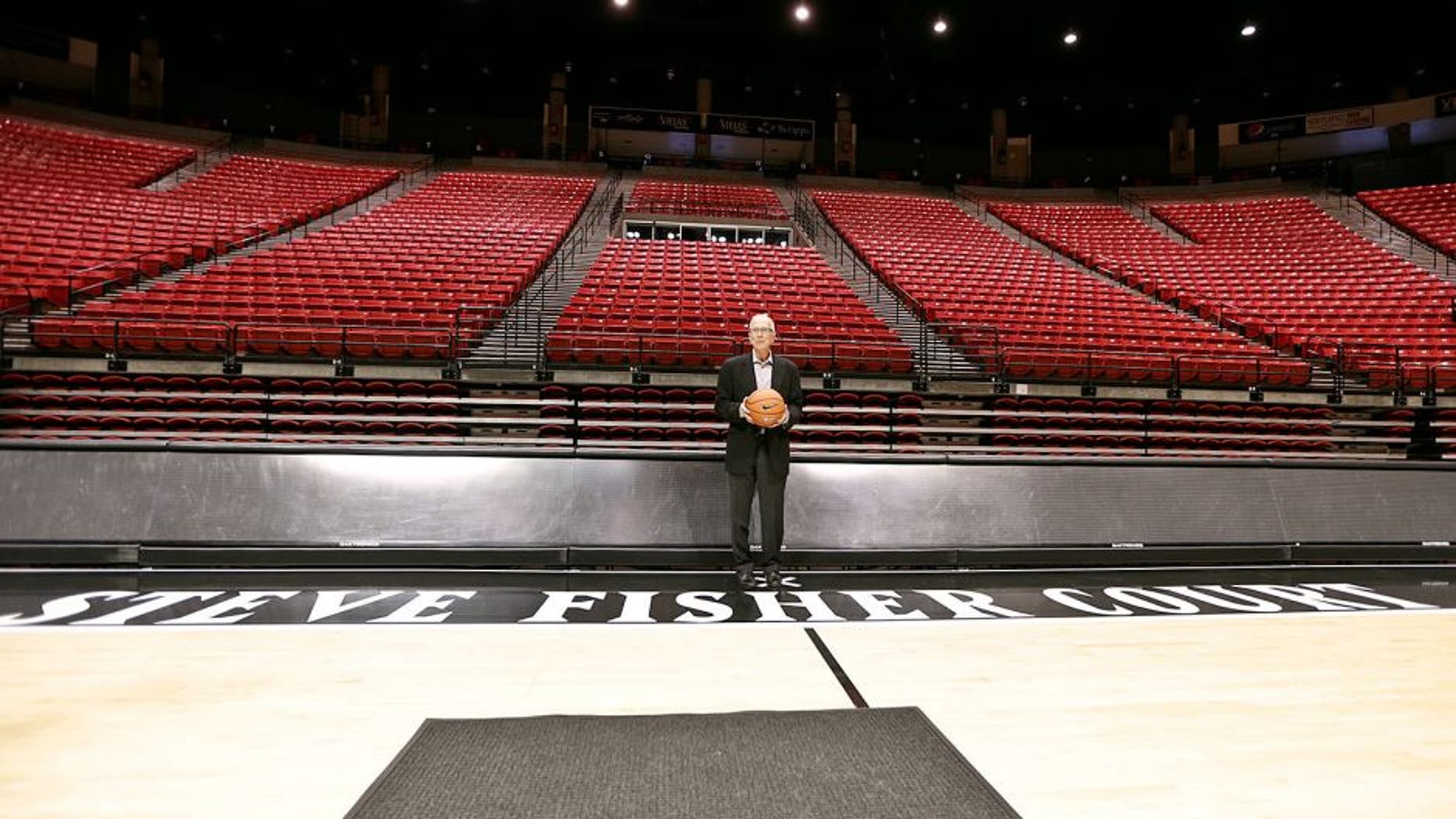 San Diego State basketball coach Steve Fisher poses along the sideline baring his name after a news conference where the floor at the Viejas Arena was named after him Thursday, Oct. 29, 2015, San Diego. (AP Photo/Lenny Ignelzi)