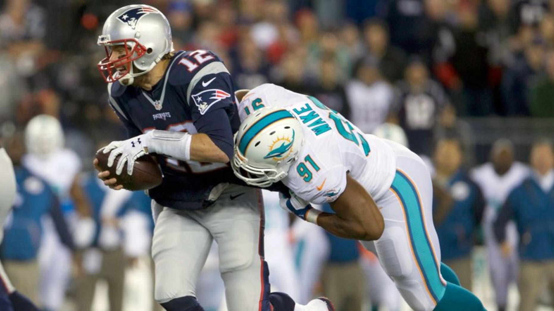 Oct 29, 2015; Foxborough, MA, USA; New England Patriots quarterback Tom Brady (12) is sacked by Miami Dolphins defensive end Cameron Wake (91) in the second quarter at Gillette Stadium. Mandatory Credit: David Butler II-USA TODAY Sports