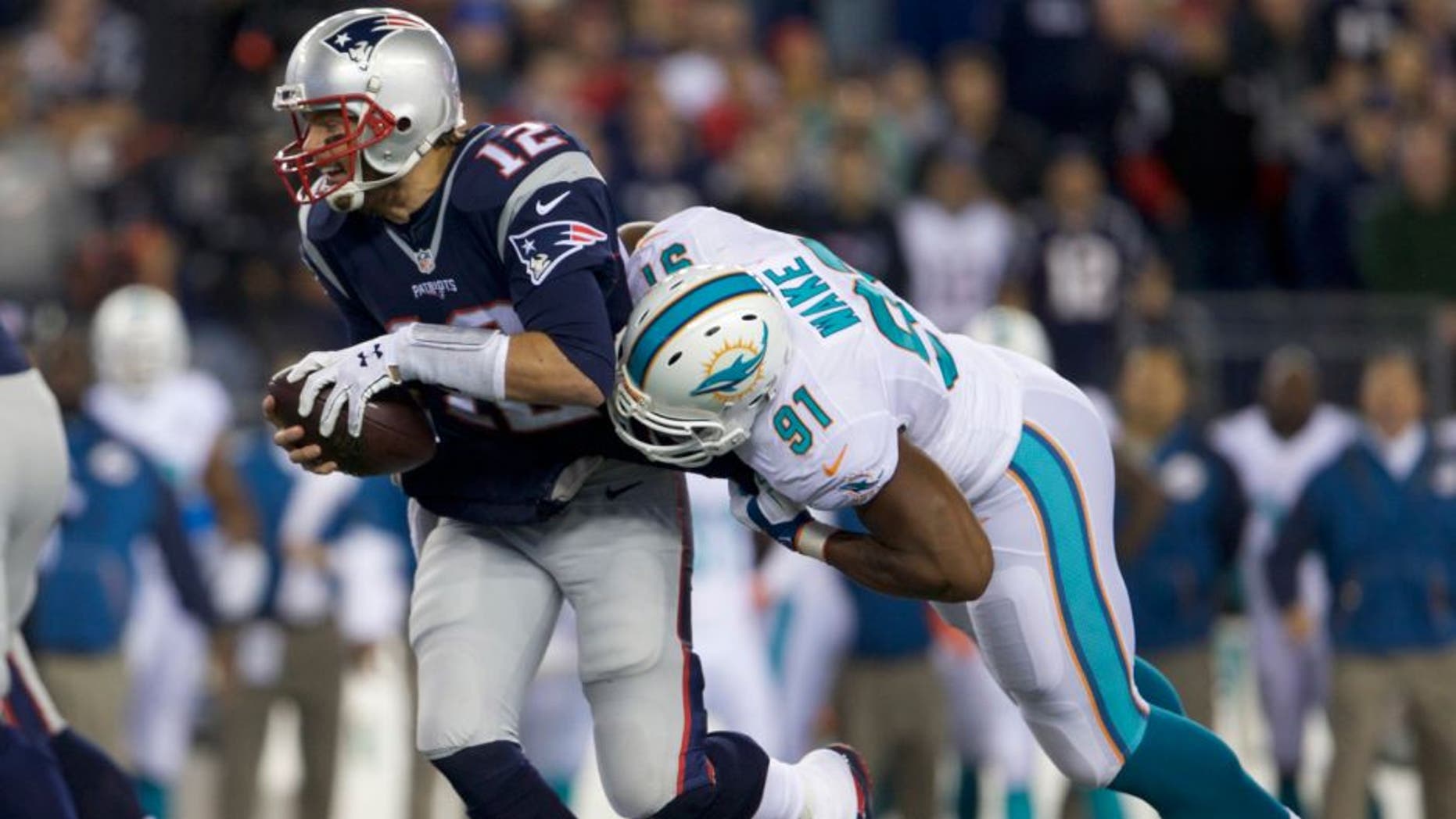 Oct 29, 2015; Foxborough, MA, USA; New England Patriots quarterback Tom Brady (12) is sacked by Miami Dolphins defensive end Cameron Wake (91) in the second quarter at Gillette Stadium. Mandatory Credit: David Butler II-USA TODAY Sports
