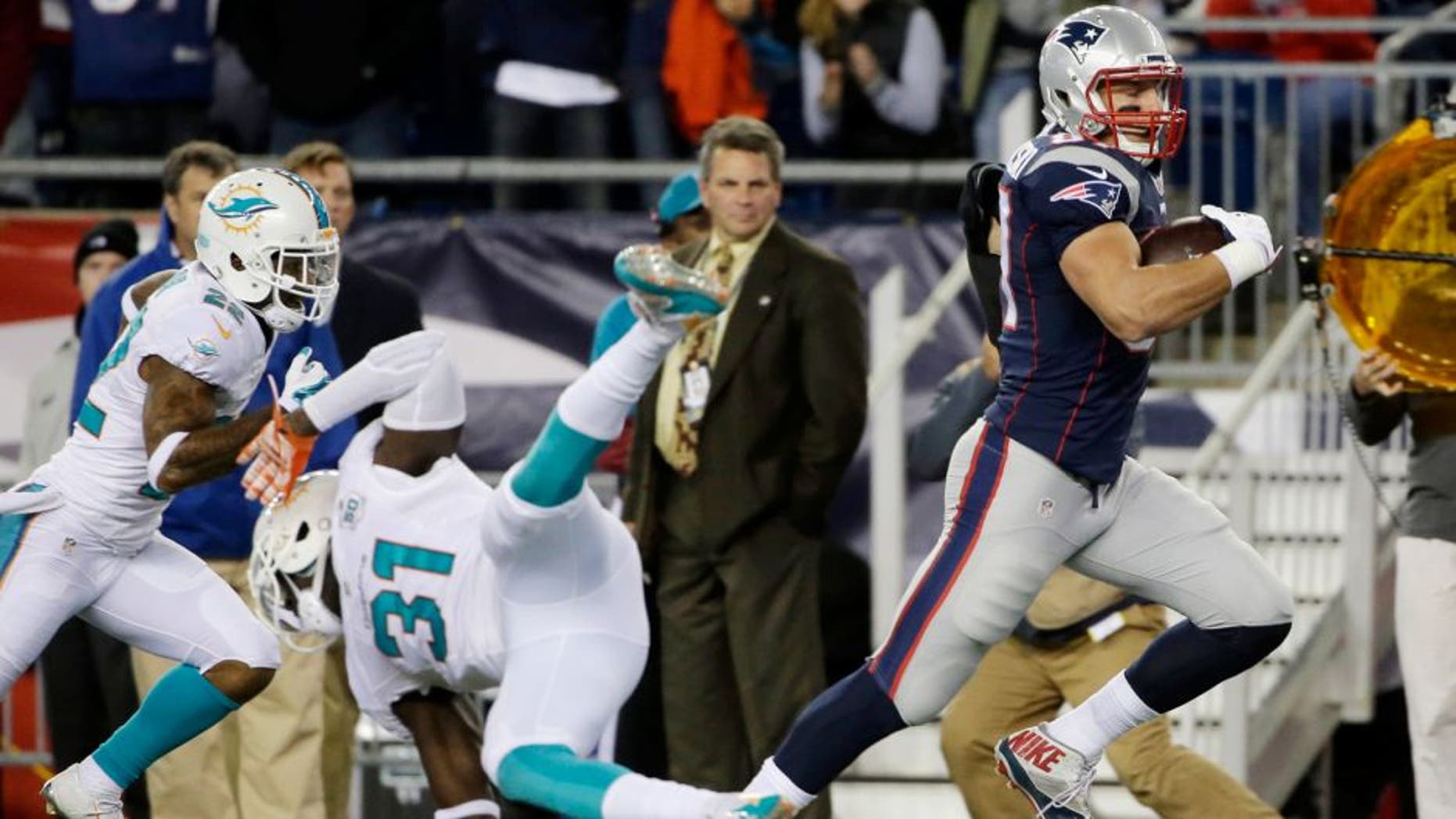 New England Patriots tight end Rob Gronkowski (87) runs past Miami Dolphins free safety Michael Thomas (31) as he heads to the end zone for a touchdown in the first half an NFL football game, Thursday, Oct. 29, 2015, in Foxborough, Mass. (AP Photo/Steven Senne)
