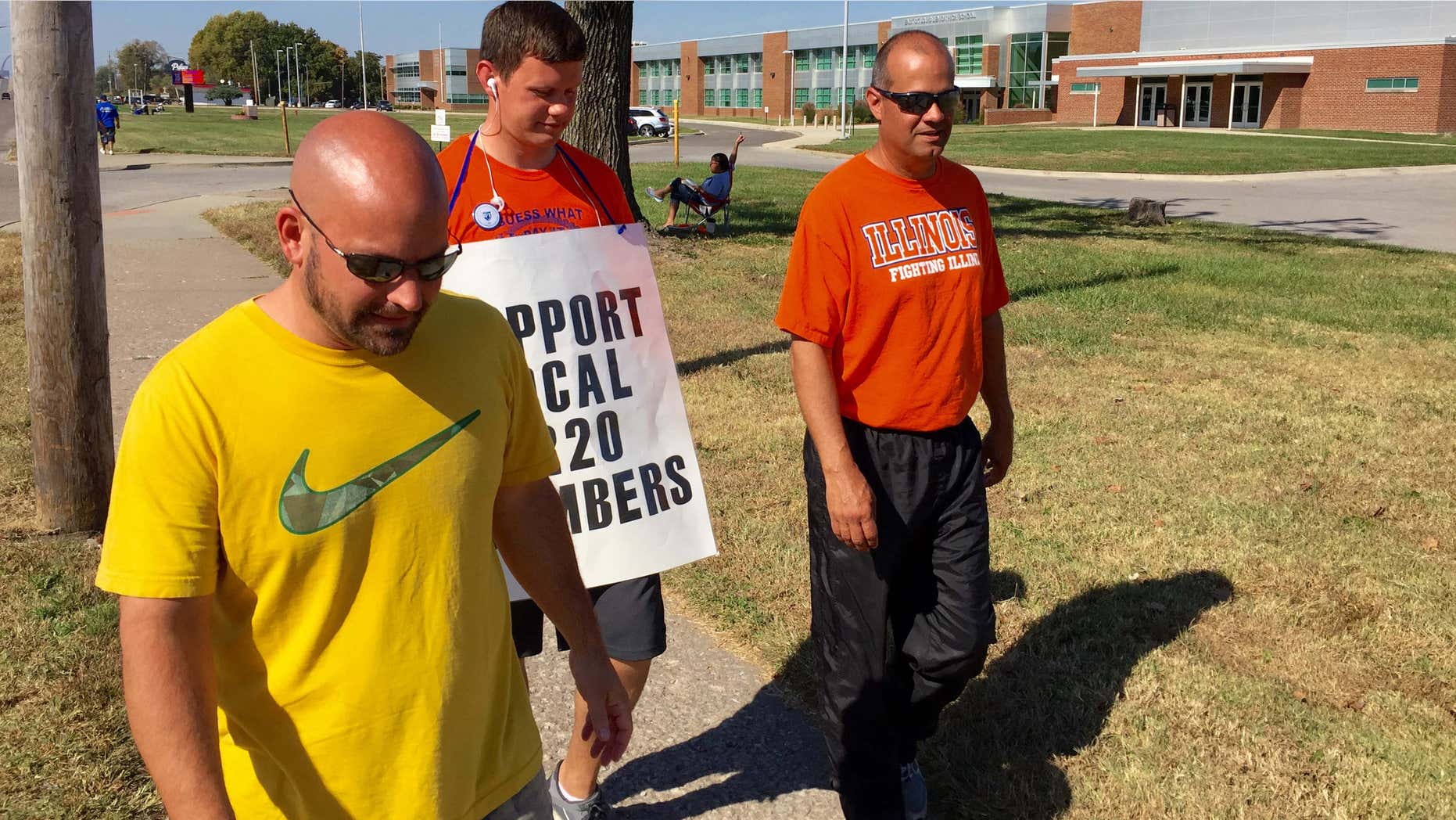 FILE - In this Oct. 27, 2015 file photo striking East St. Louis teachers, from left, Jeff Schneider, Josh Cummins and Paul Thies walk the picket line in front of East St. Louis Senior High School in East St. Louis, Ill.