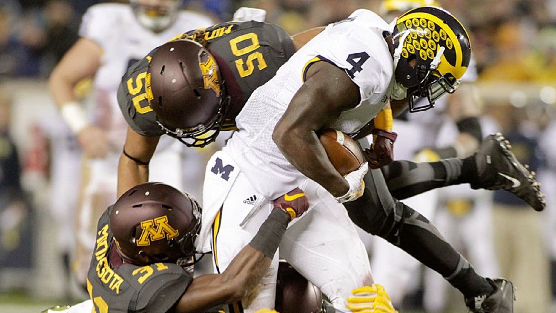 Michigan running back De'Veon Smith (4) is tackled by Minnesota's Eric Murray (31) and Jack Lynn (50) after a 15 yard catch and run during the first half of an NCAA college football game Saturday, Oct. 31, 2015, in Minneapolis.(AP Photo/Paul Battaglia)