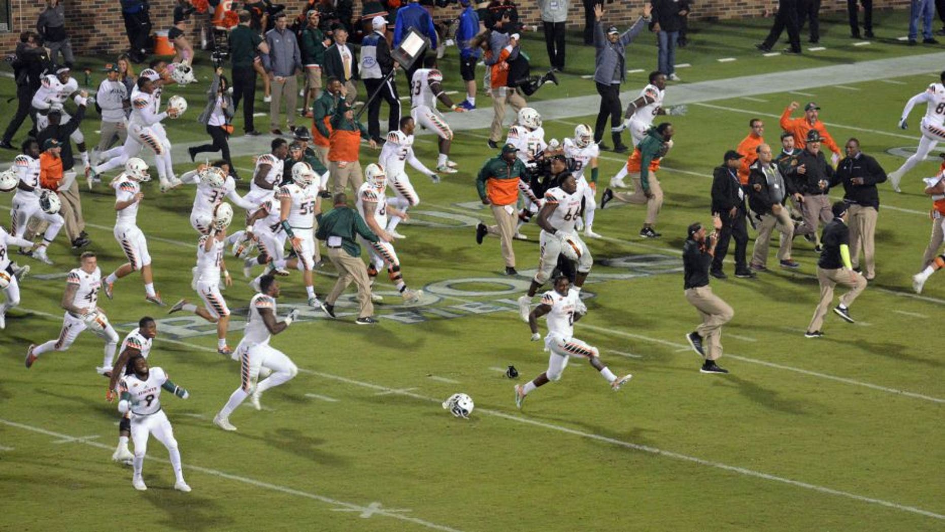 Miami players run onto the field to celebrate their 30-27 win over Duke in the final seconds of an NCAA college football game in Durham, N. C. (Bernard Thomas/The Herald-Sun via AP)