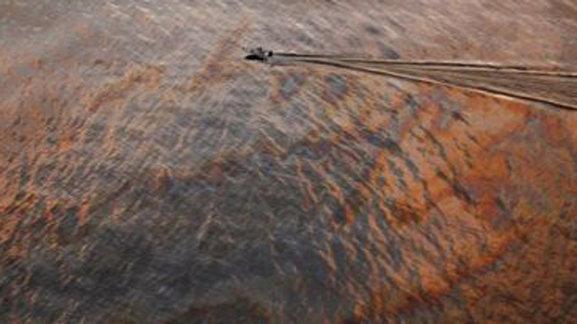 FILE- A boat motors through oil sheen from the Deepwater Horizon oil spill off East Grand Terre Island, where the Gulf of Mexico meets Barataria Bay, on the Louisiana coast, at sunset.