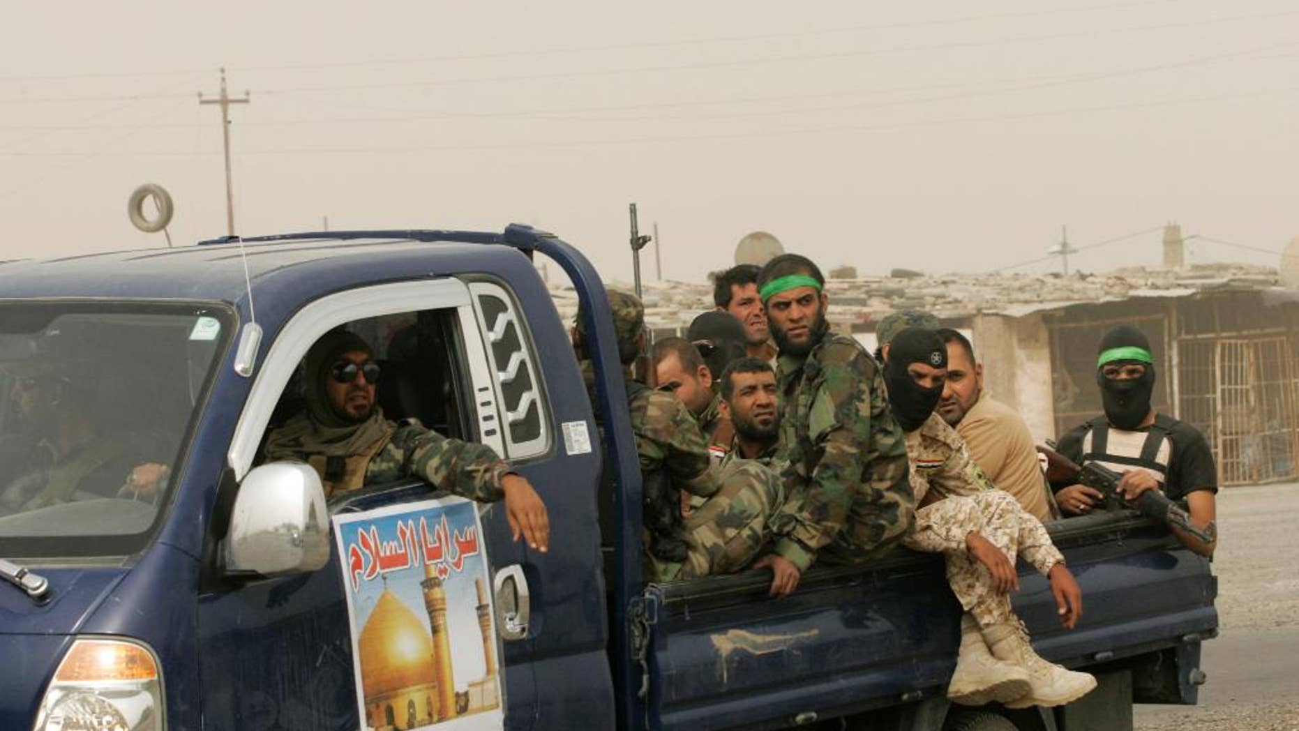 In this Saturday, July 12, 2014 photo, Iraq Shiite fighters with the "Peace Brigades" patrol during a sand storm in Samarra, 60 miles (95 kilometers) north of Baghdad, Iraq. Fighters of the voluntary armed group formed after the radical Shiite cleric Muqtatda al-Sadr called to protect holy shrines against possible attacks by Sunni militants have been deployed to protect the Shiite holy al-Askari shrine in the city of Samarra. Islamic extremists have destroyed at least 10 ancient shrines and Shiite mosques in territory - the city of Mosul and the town of Tal Afar - they have seized in northern Iraq in recent weeks. (AP Photo)