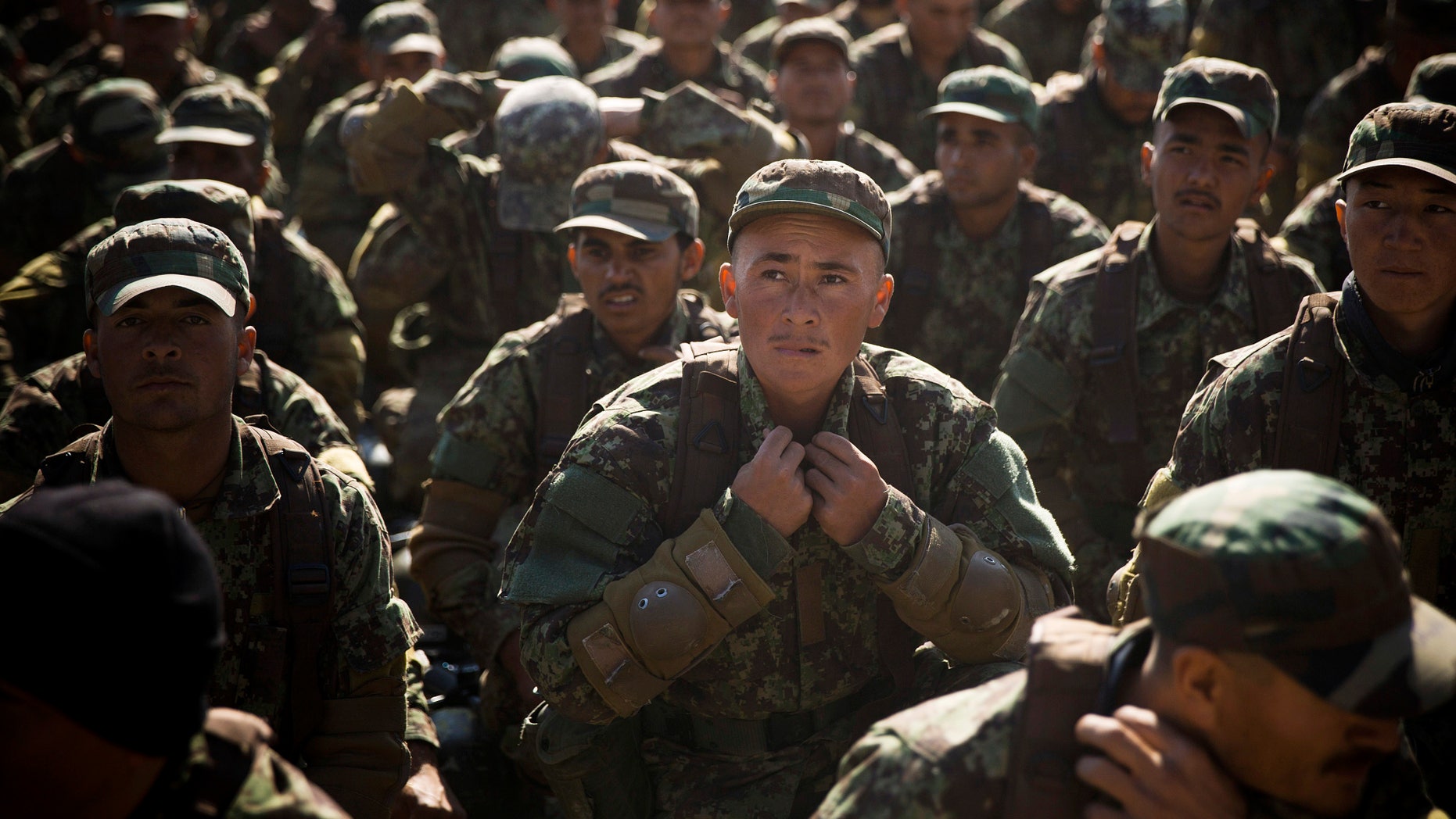 FILE - In this Tuesday, Nov. 26, 2013 file photo, an Afghan army soldier adjusts his uniform during an outdoor lesson at a training facility in the outskirts of Kabul, Afghanistan. Federal inspectors said Tuesday, Jan. 28, 2014 that a $200 million U.S. program to improve the literacy of Afghan soldiers has had limited impact and most likely won’t hit its goals.(AP Photo/Anja Niedringhaus, File)