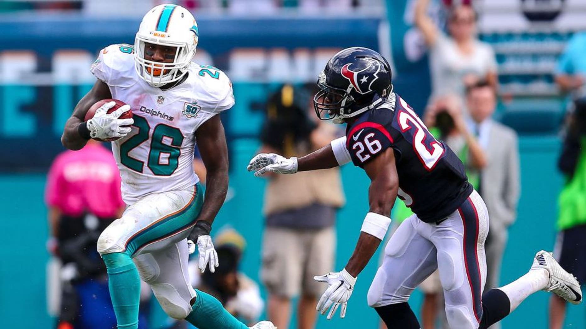 Oct 25, 2015; Miami Gardens, FL, USA; Miami Dolphins running back Lamar Miller (26) runs past Houston Texans defensive back Rahim Moore (26) during a game at Sun Life Stadium. Mandatory Credit: Steve Mitchell-USA TODAY Sports