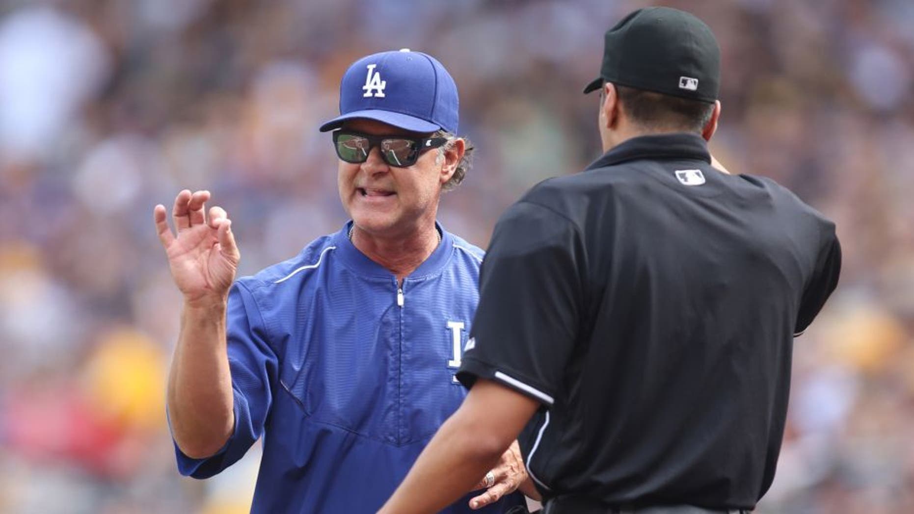Aug 8, 2015; Pittsburgh, PA, USA; Los Angeles Dodgers manager Don Mattingly (L) talks with home plate umpire Gabe Morales (R) against the Pittsburgh Pirates during the first inning at PNC Park. Mandatory Credit: Charles LeClaire-USA TODAY Sports