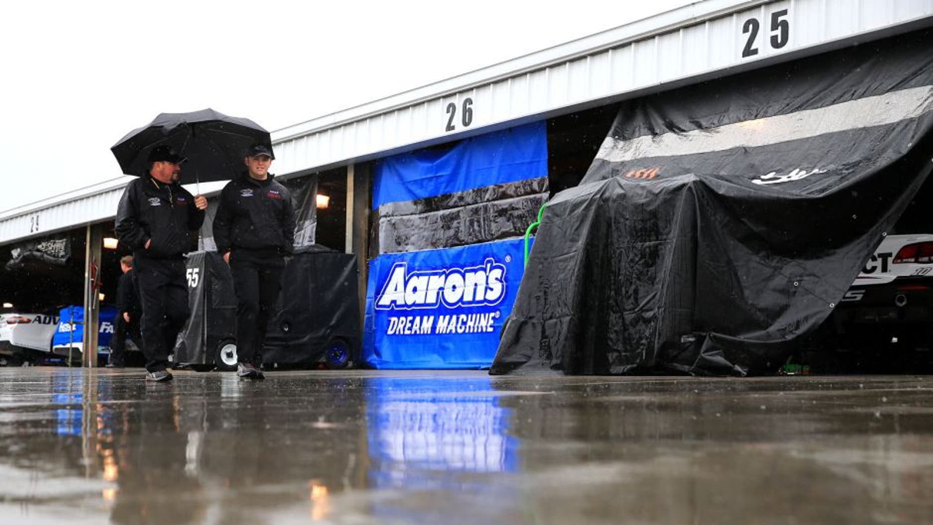 MARTINSVILLE, VA - MARCH 27: Crew members walk through the garage area as it rains prior to practice for the NASCAR Sprint Cup Series STP 500 at Martinsville Speedway on March 27, 2015 in Martinsville, Virginia. (Photo by Daniel Shirey/Getty Images)